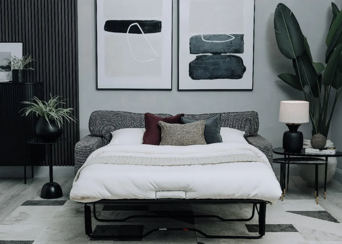 A lifestyle image of the Nevada sofabed made up as a bed with Intense & Mode canvas on wall and side tables.