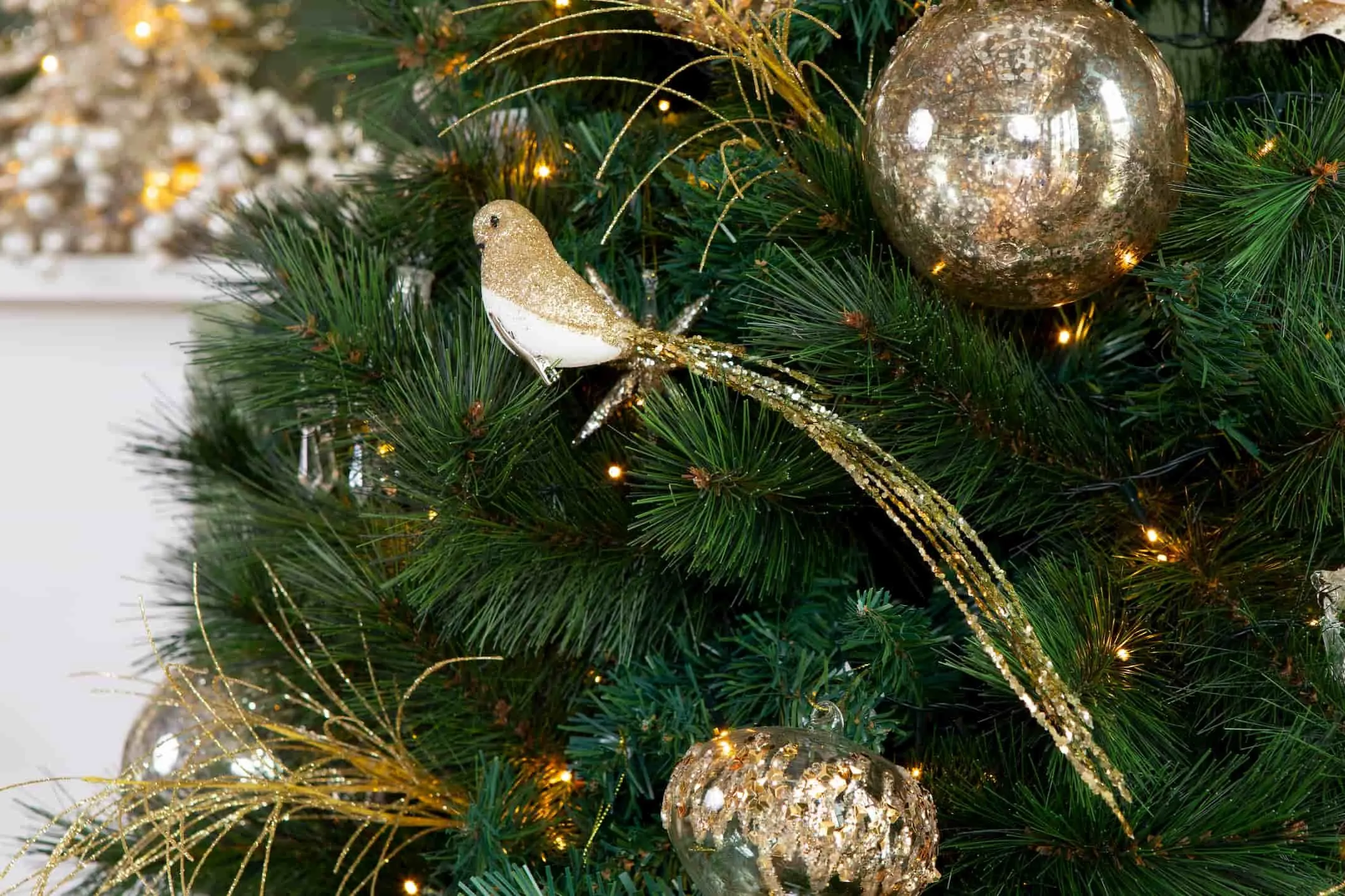 Christmas Gold Bird with long tail in lifestyle image set on a tree