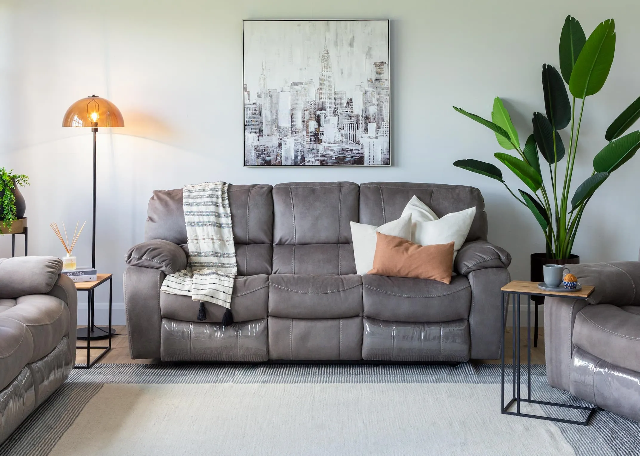 A lifestyle image of the Bradford grey 3 seater sofa in fixed mode with the Aston tables & Mellan floor lamp.