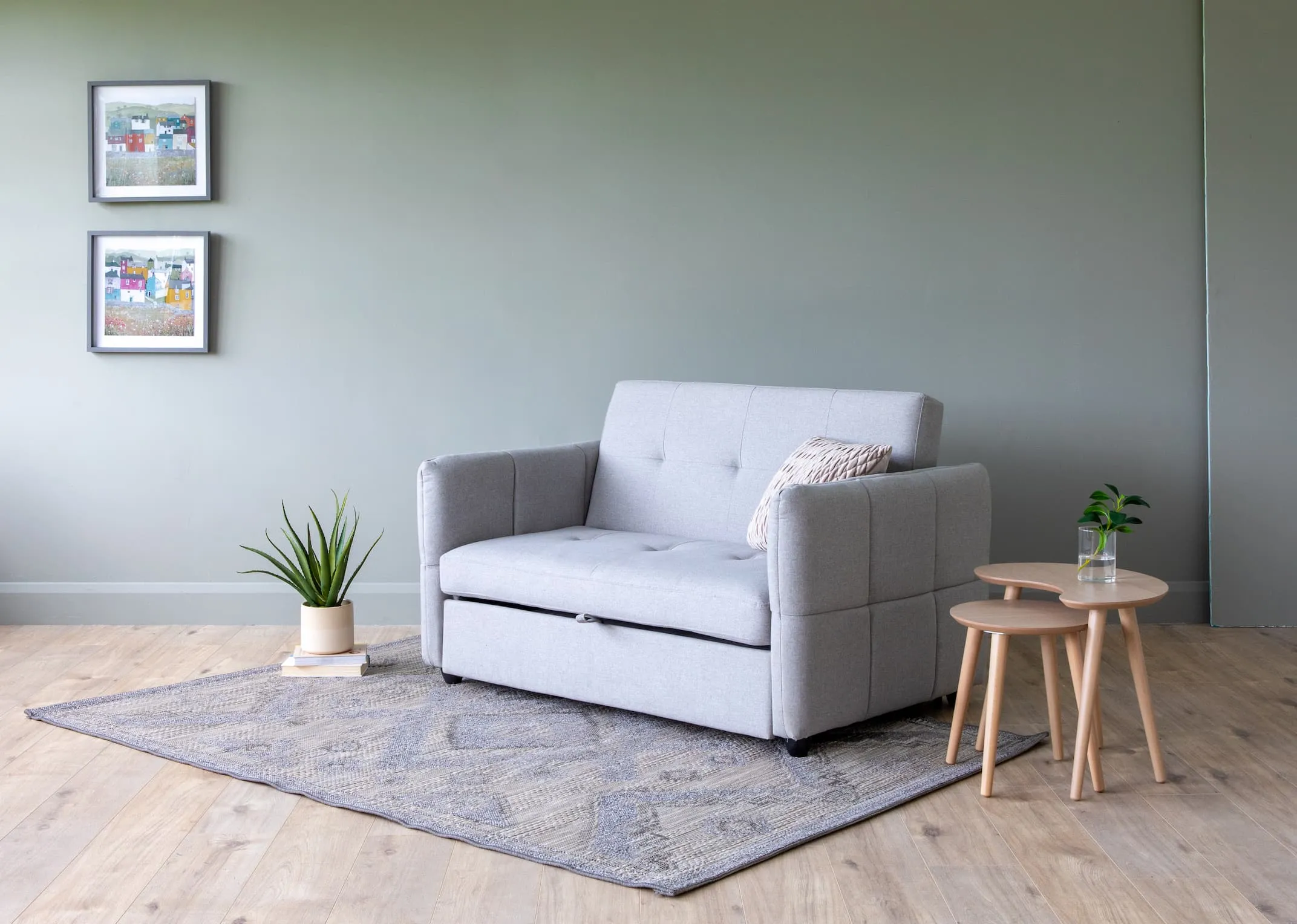 A lifestyle image of the Celeste Sofa bed with dansk tables & 2 sister house prints.