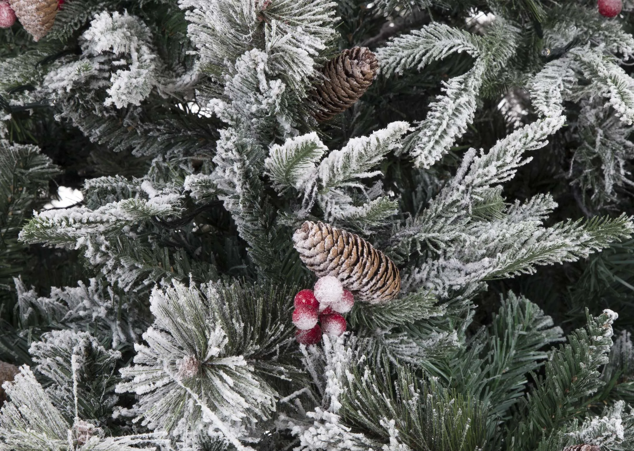 A close-up view of an 8 foot xmas tree with snow covered branches berries and acorns