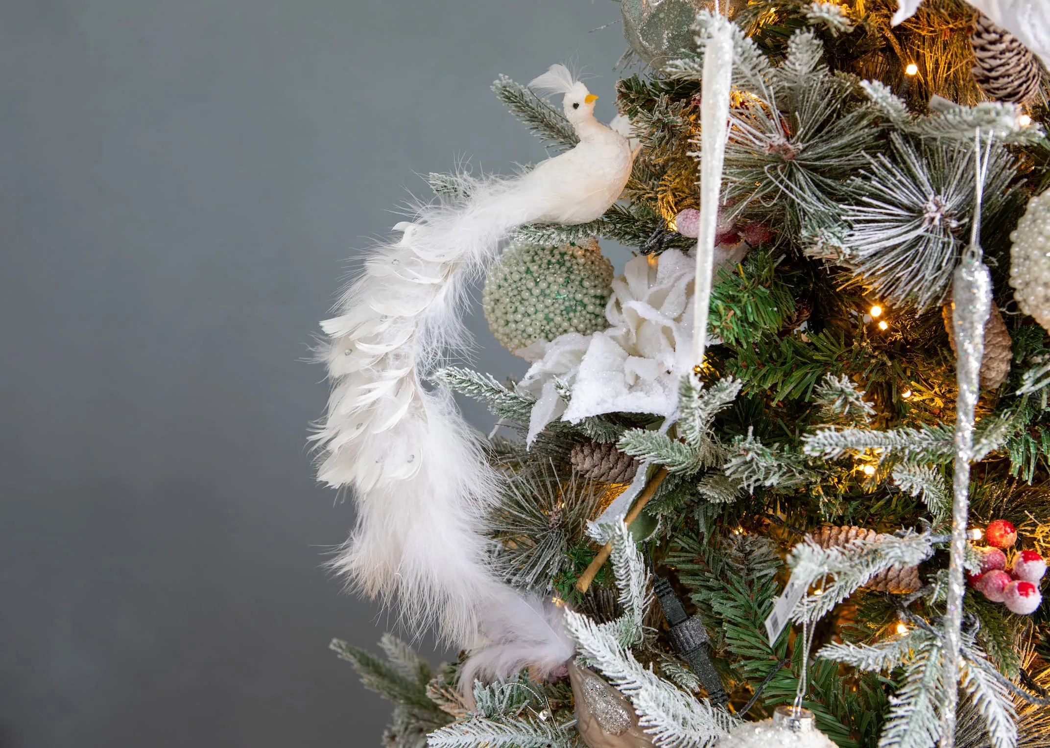 A lifestyle image of the white bird 25cm with feathers & Xmas spray on Christmas tree.