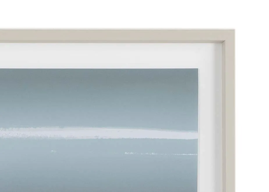 A beige framed print with a coastal landscape called Sapphire from Ulyana Hammond. Closeup View.
