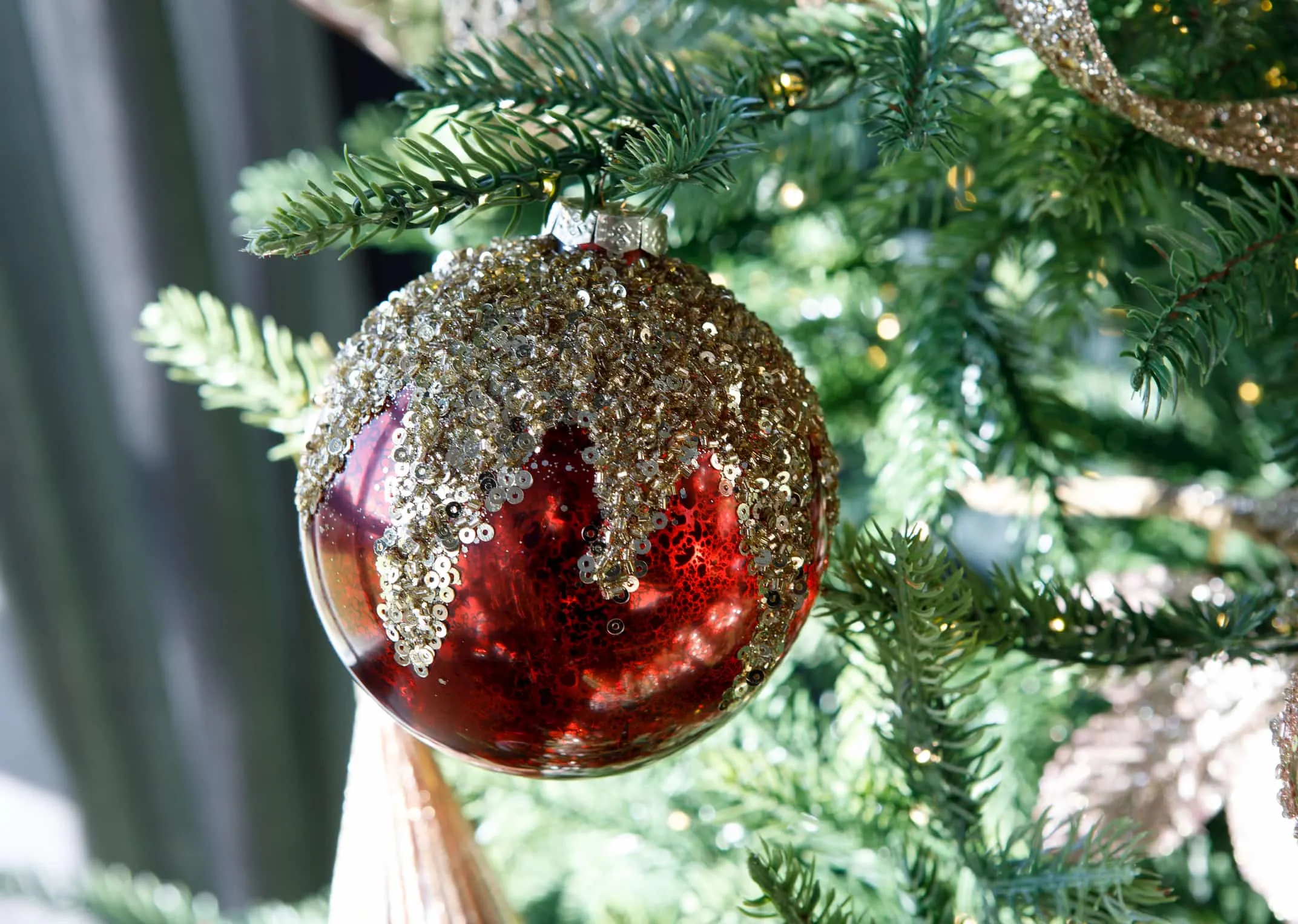 A red metallic bauble topped with gold seuins from EZ Living Furniture's Christmas Collection. Closeup of gold sequins