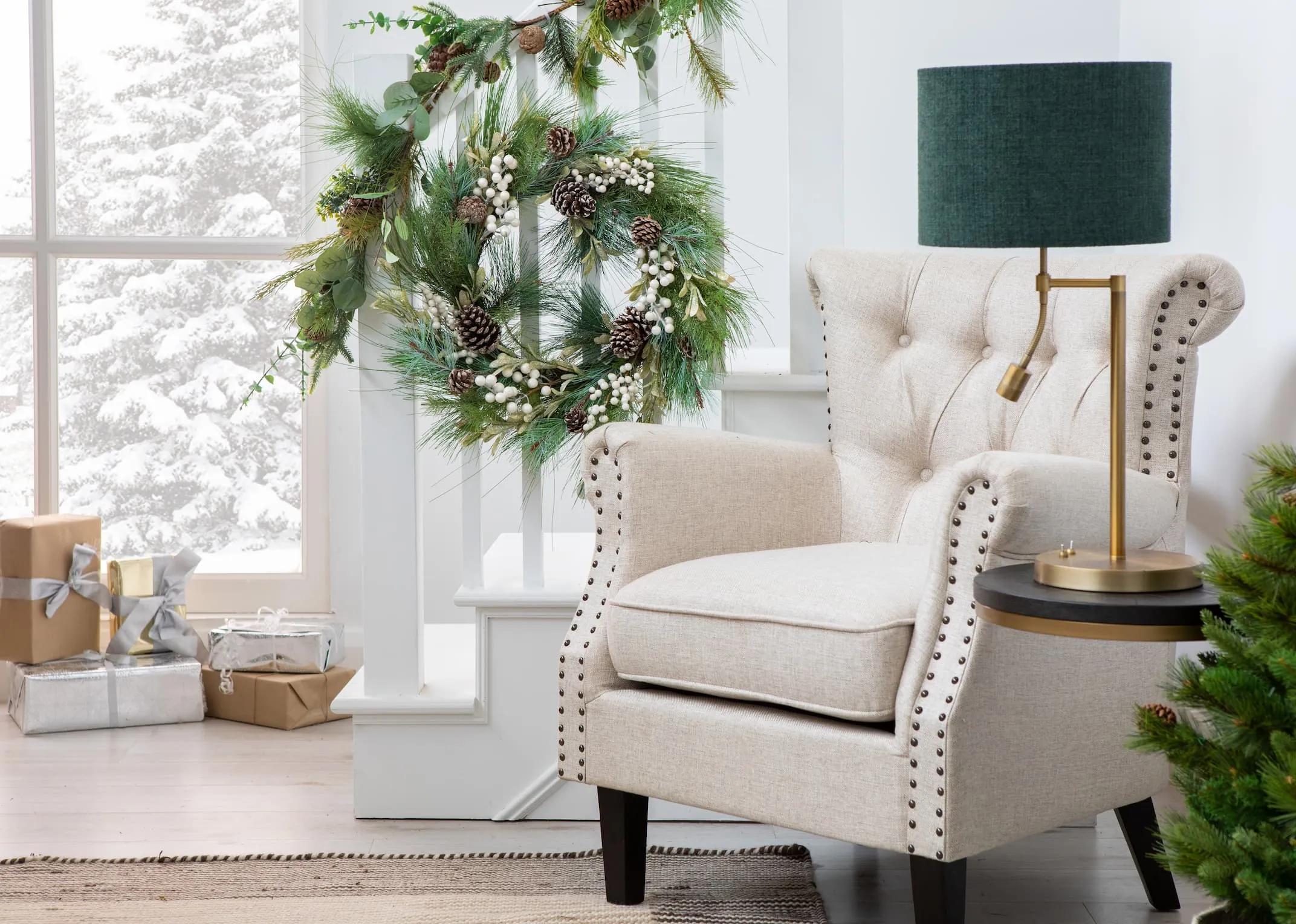 A creative lifestyle image of the Sara Cream Armchair with the pearl & Pine cone wreath hanging from stairs wit lush garland