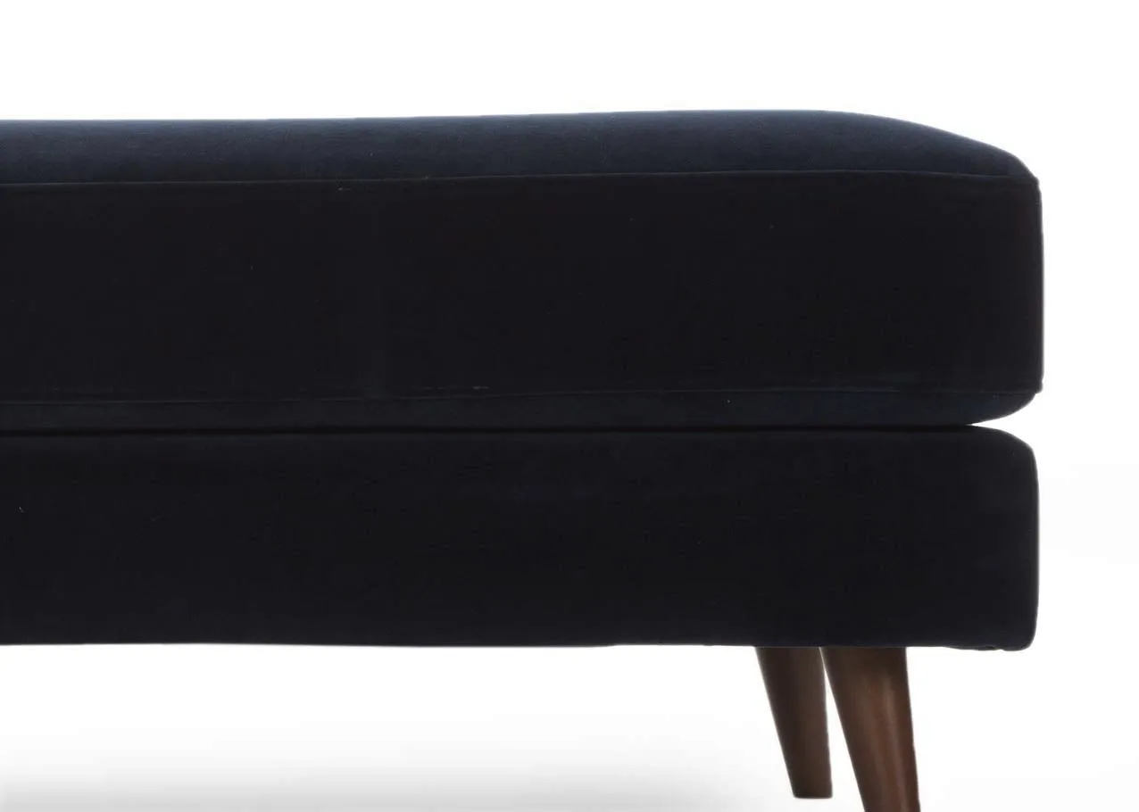 A large navy velvet footstool with dark wood feet from EZ Living Furniture's Bellini range. Closeup of fabric edge