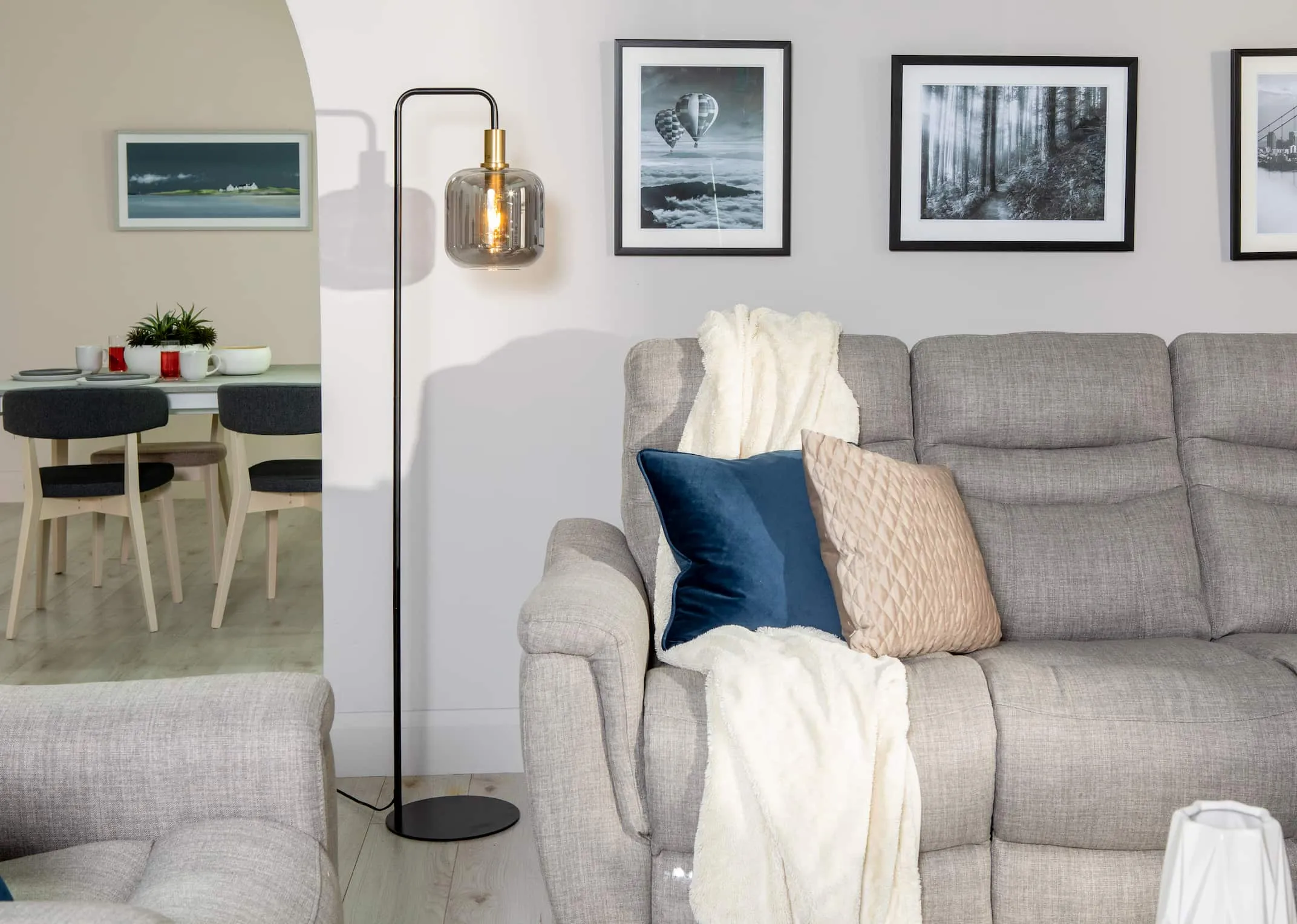 A lifestyle image of the Lekar lamp on beside the Flair silver sofa & woodland stroll
