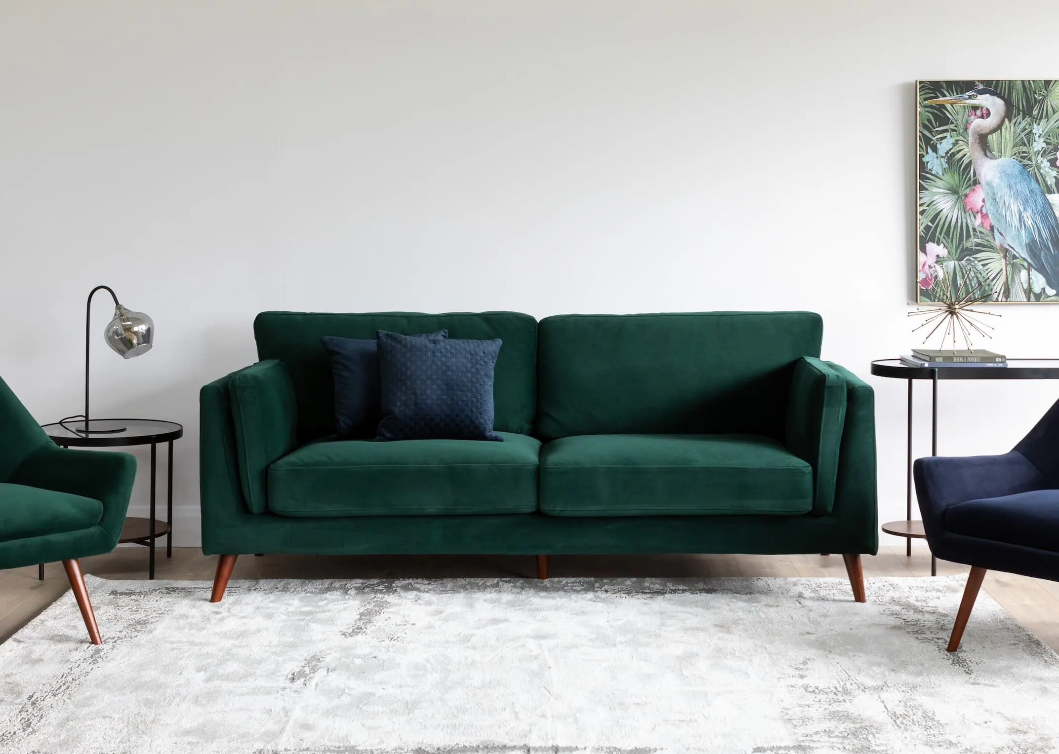 A lifestyle image of the Green Bellini sofa with Janey Armchairs in navy & green with glam living range & statuesque print.