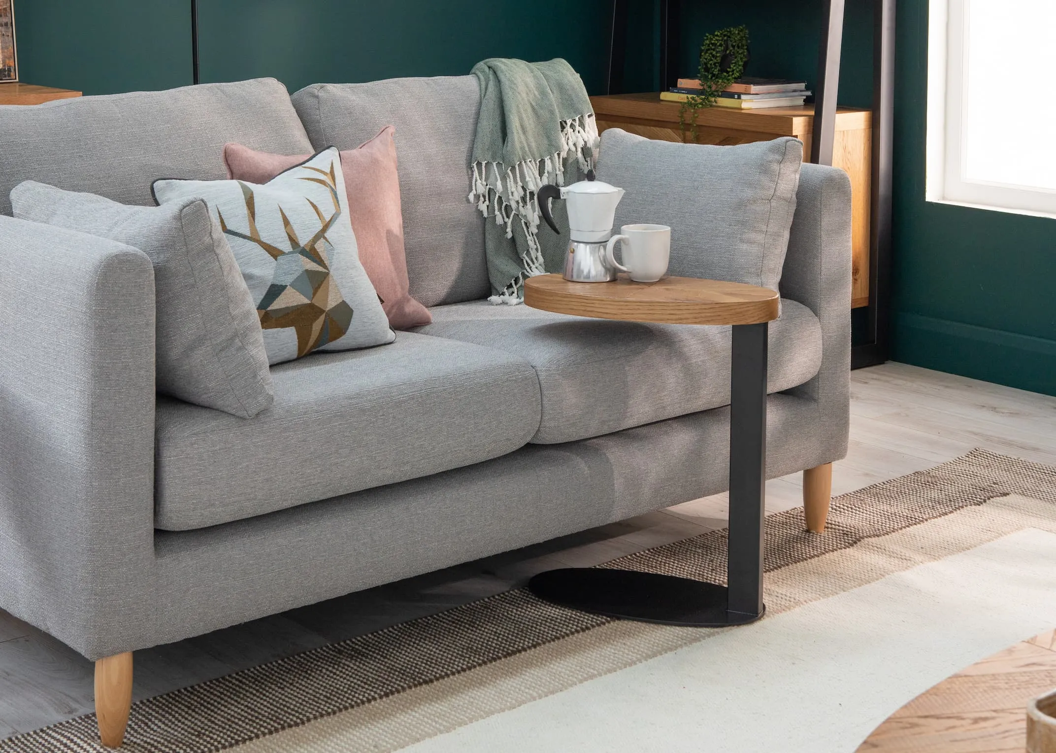 A lifestyle image of the Alamo 2 Seater grey sofa with Ellipse sofa table.