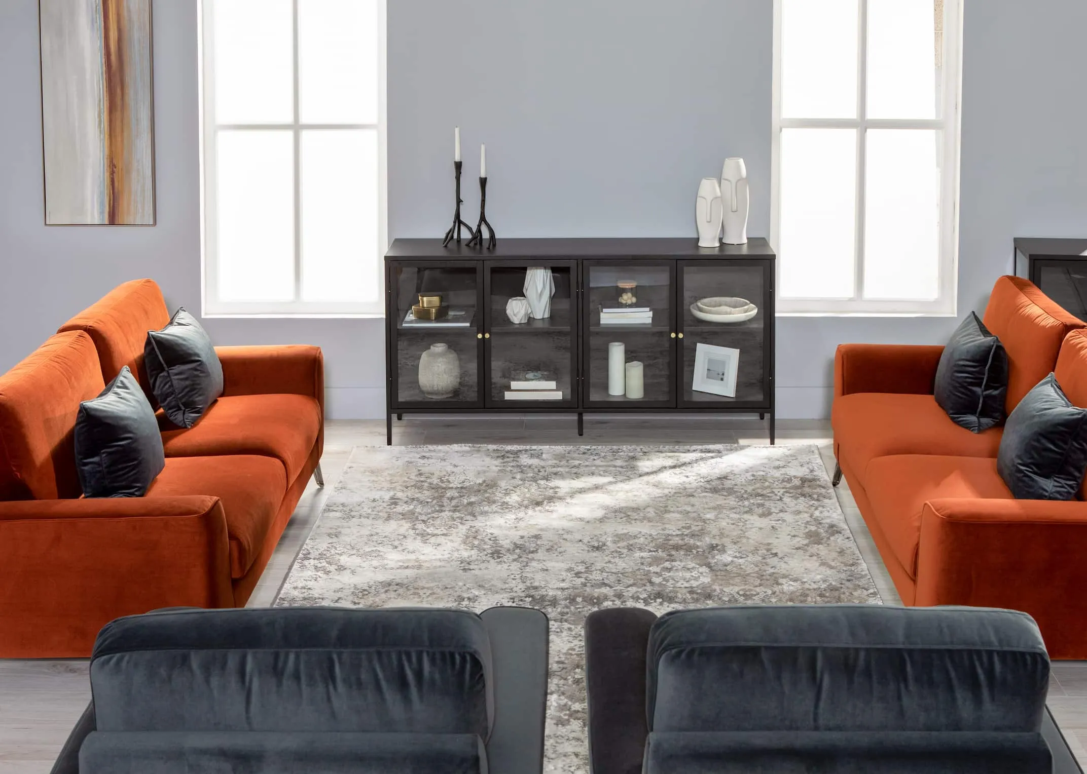 A lifestyle image of the Megan Sofas in rust & grey with Carmel Cabinet & Omar Candle holders