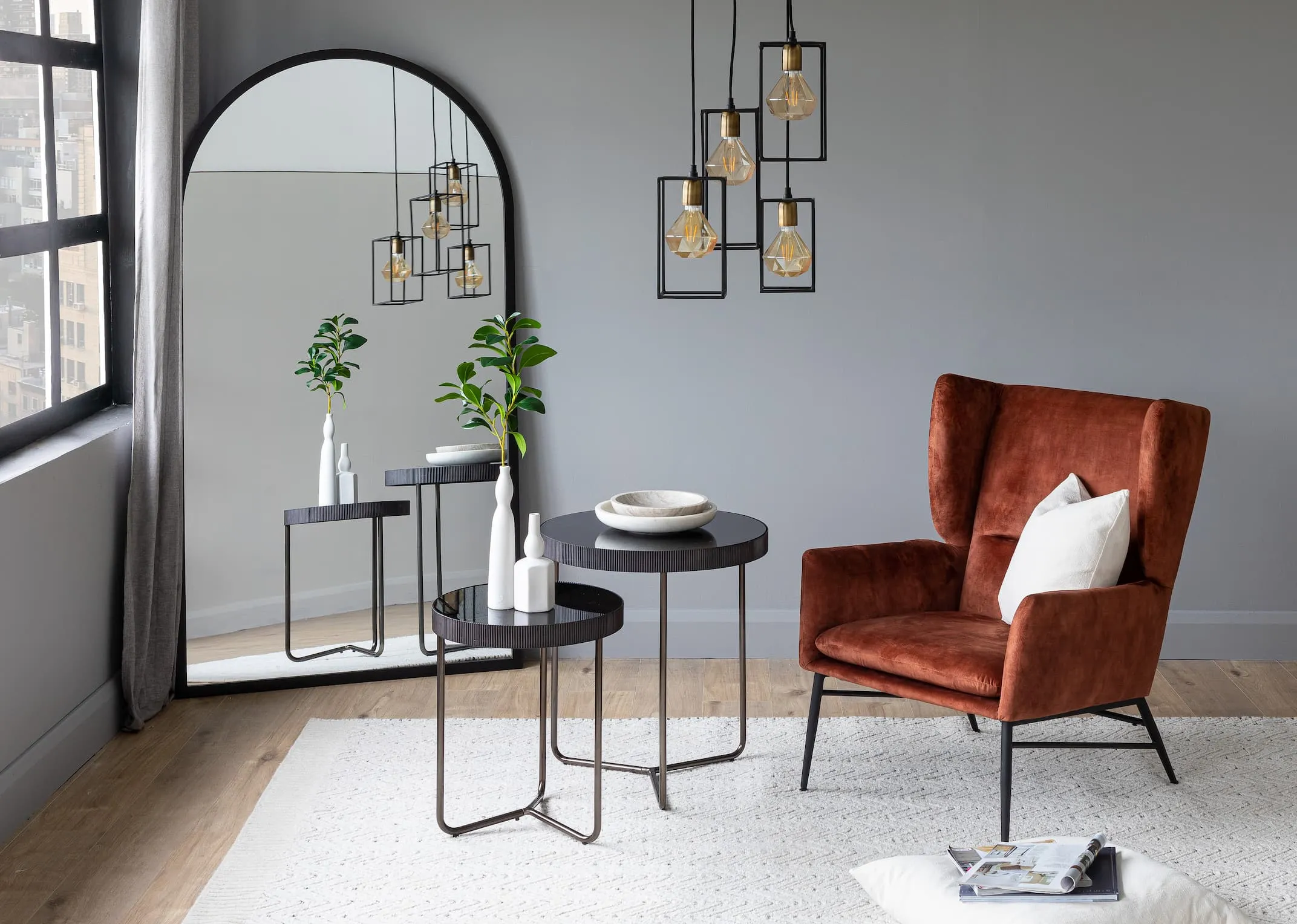 A lifestyle image of the Chrisley mirror with boston armchair with mandy nest of tables and marey ceiling light.