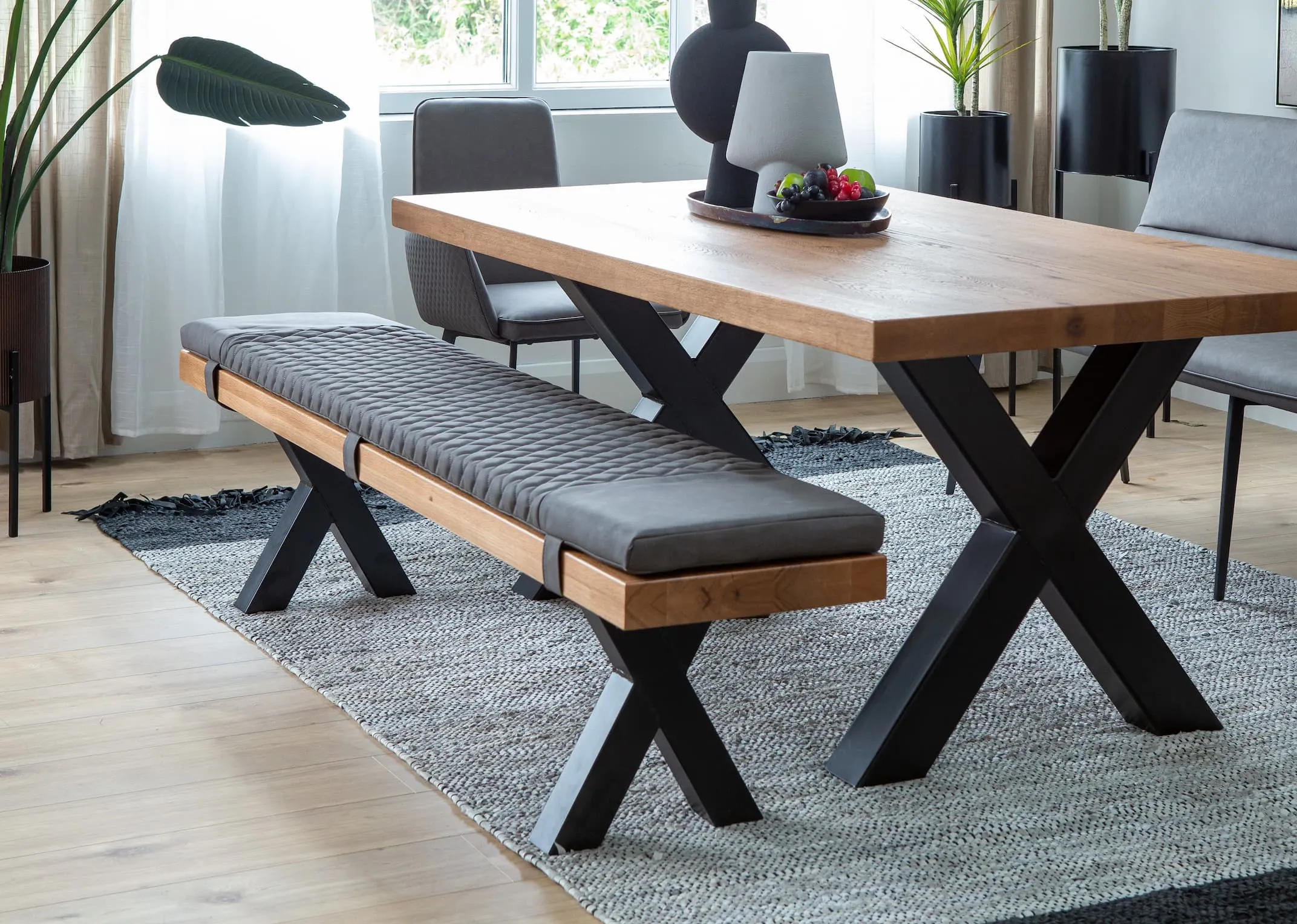 A lifestyle image of the Lucca Dining Table & Bench and grey seat pad on the Vagium rug