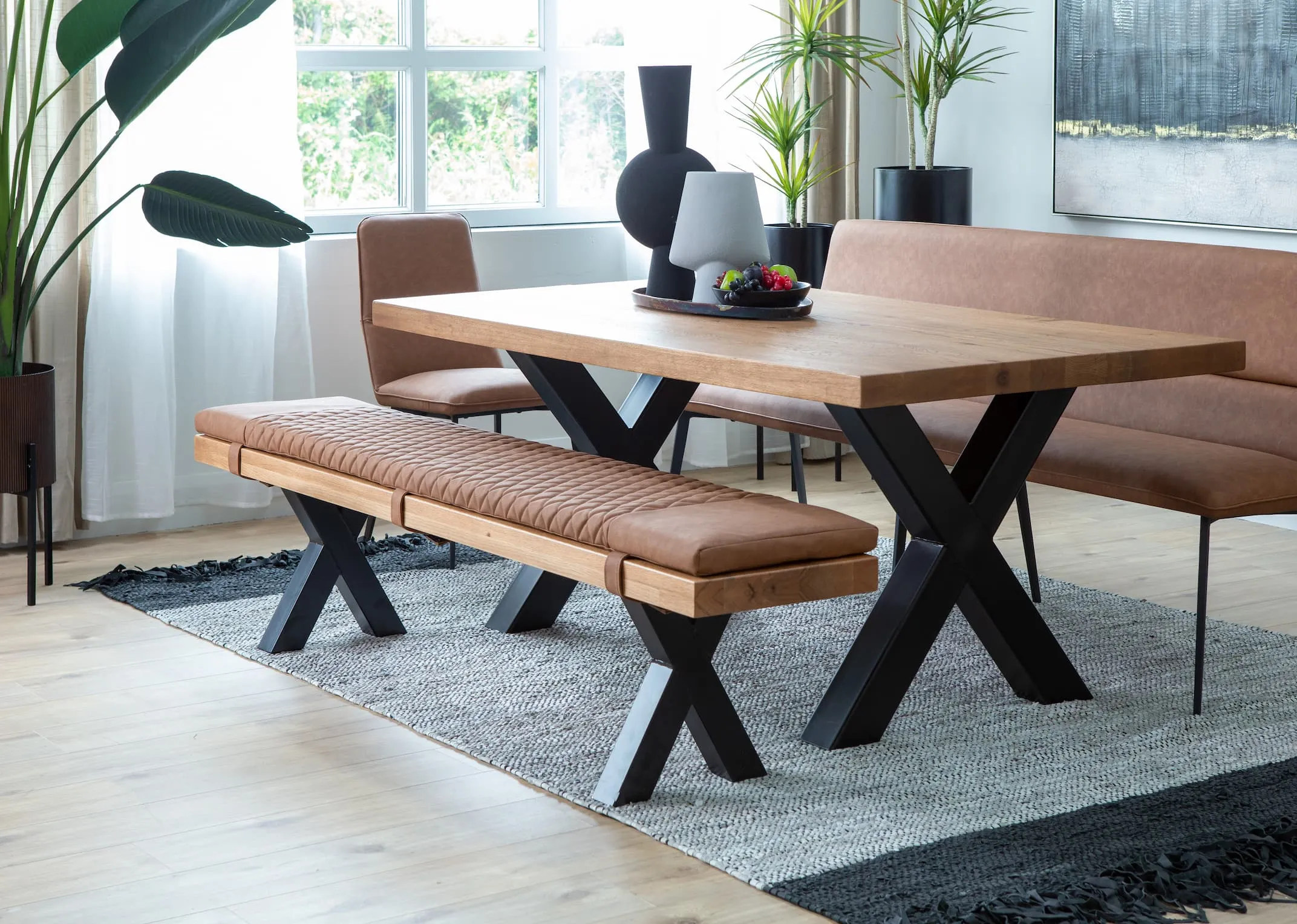 A lifestyle image of the Lucca Dining Table & Bench and tan seat pad on the Vagium rug