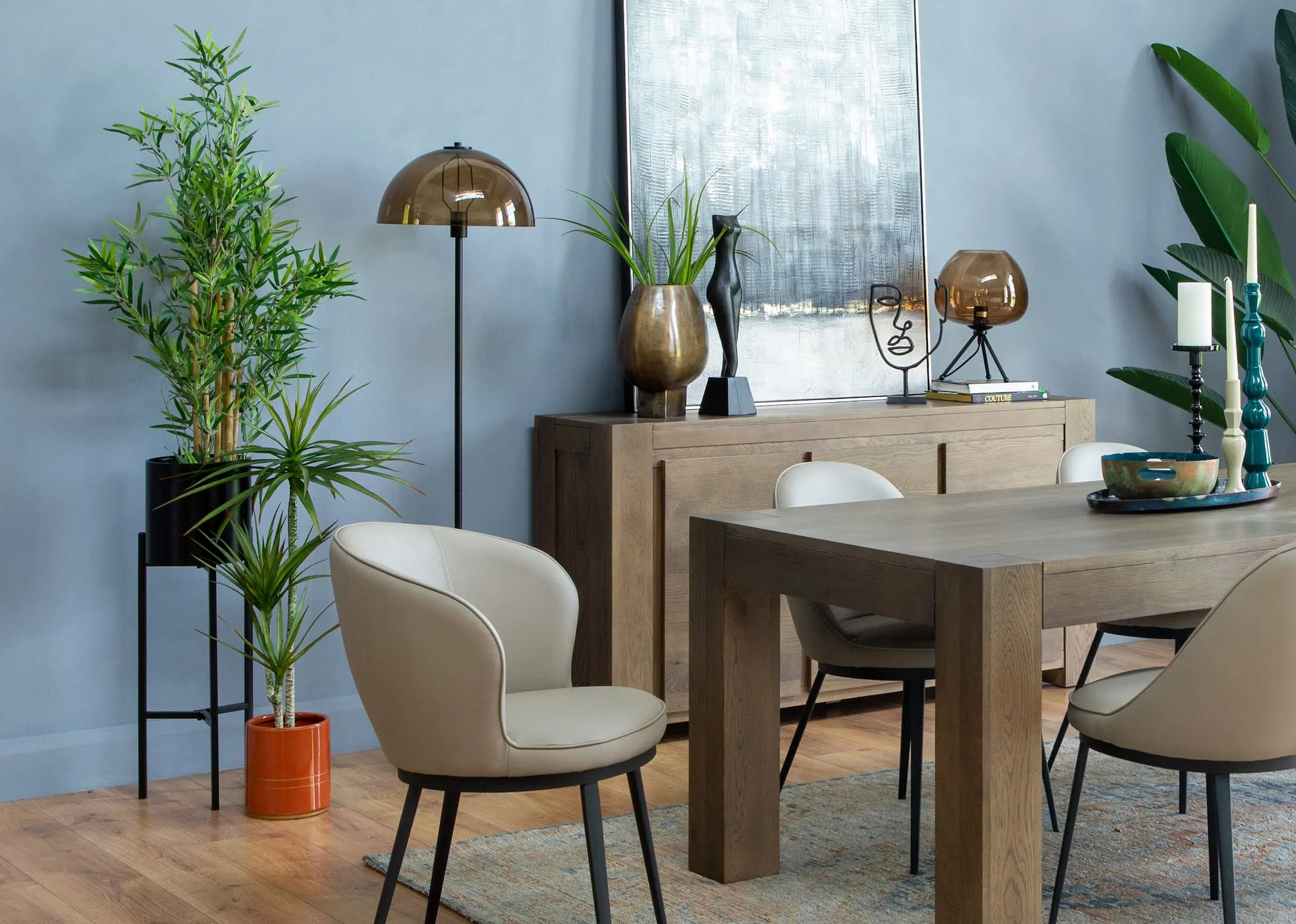 A lifestyle image of the Morgan Dining table with Gain chairs & Bamboo plant in a breston pot holder.