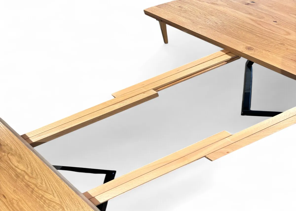 An oak round to oval extendable dining table from EZ Livings Renvyle range. Side view of metal frame