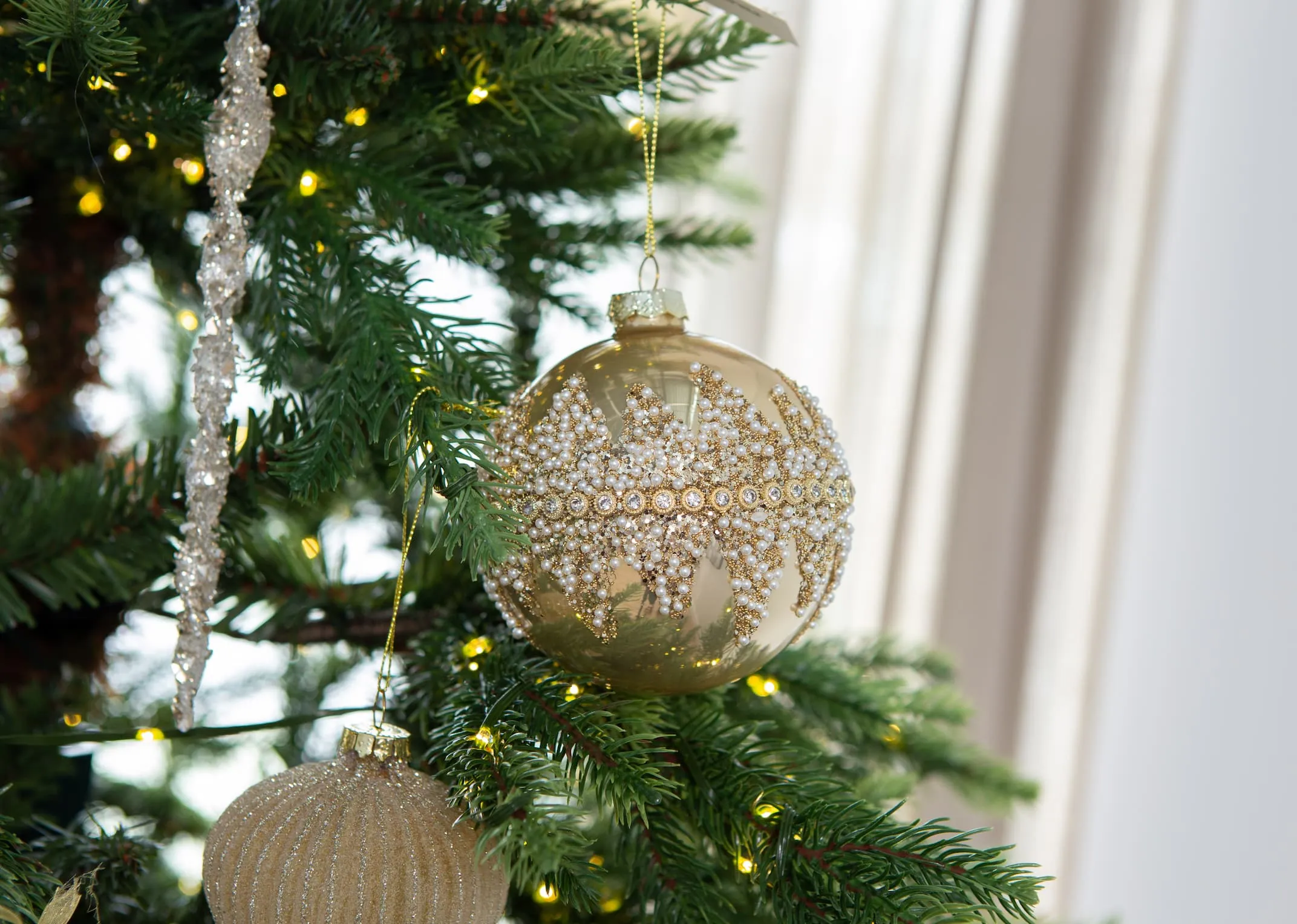 A lifestyle image of the Encrusted gold bauble on an EZ Living Cnhristmas range.
