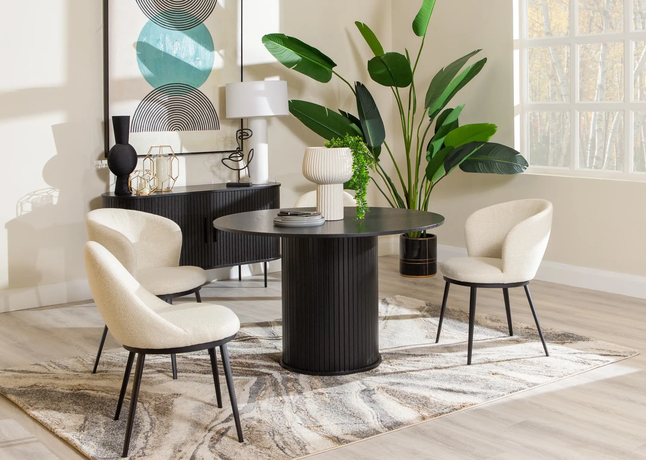 A lifestyle image of the Nola black oak round dining table with the Gain boucle dining chairs and carver chairs