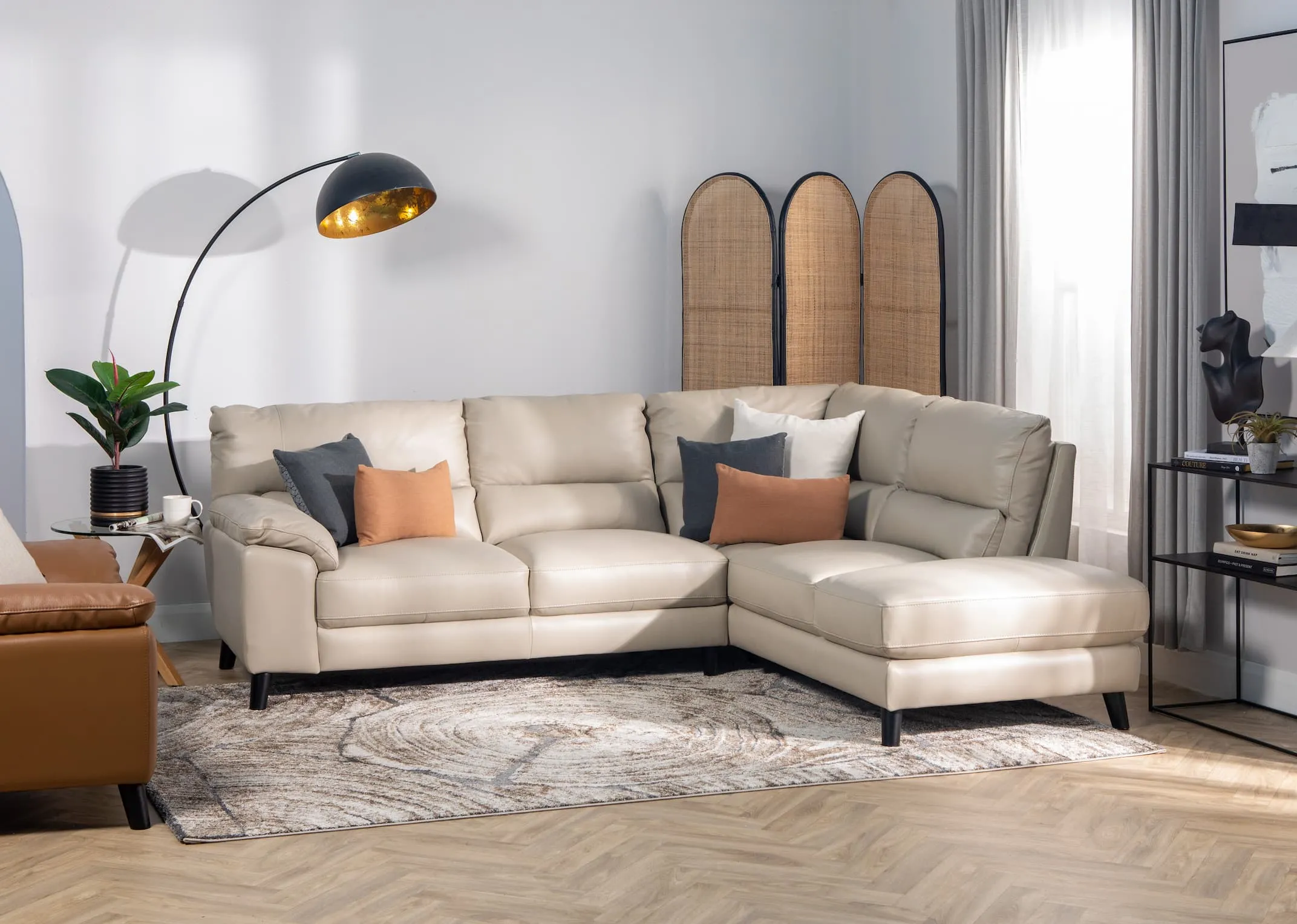 A lifestyle image of the Alfredo grey corner chaise with alfredo brown armchair with herwin divider and pebble console table