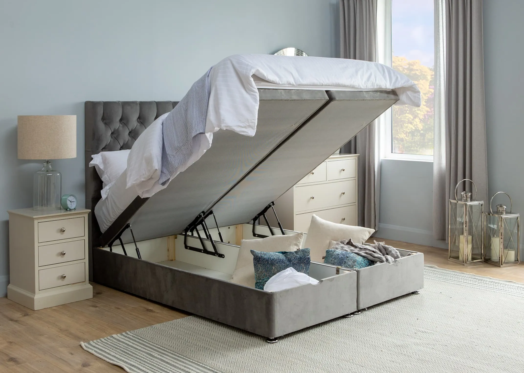 A lifestyle image for the Ottoman bed open to reveal hidden storage and paired with the Palma Headboard.