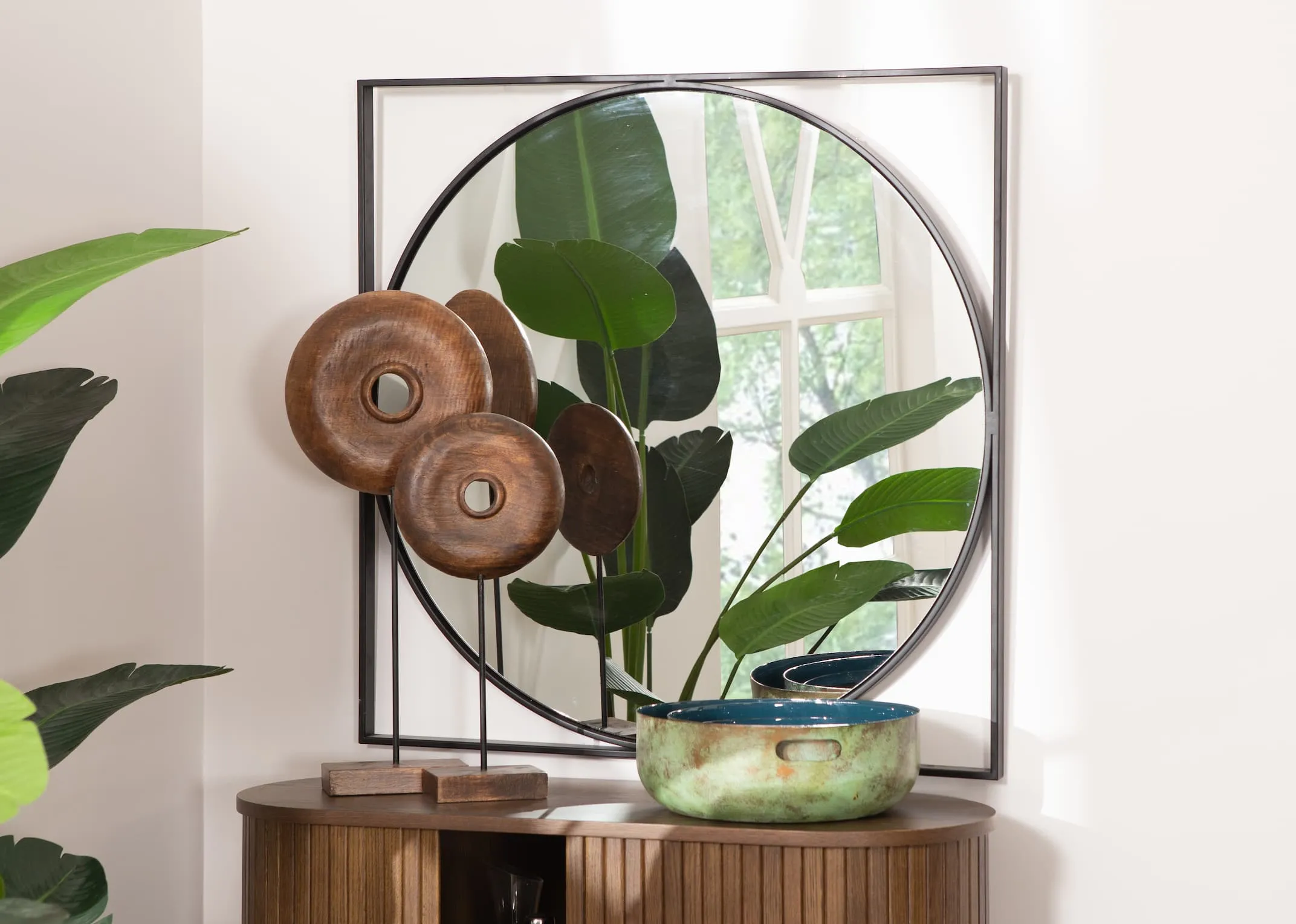 A lifestyle image of the Lyra Mirror with Xerra Wood ornaments on top of the Nola Oak Sideboard
