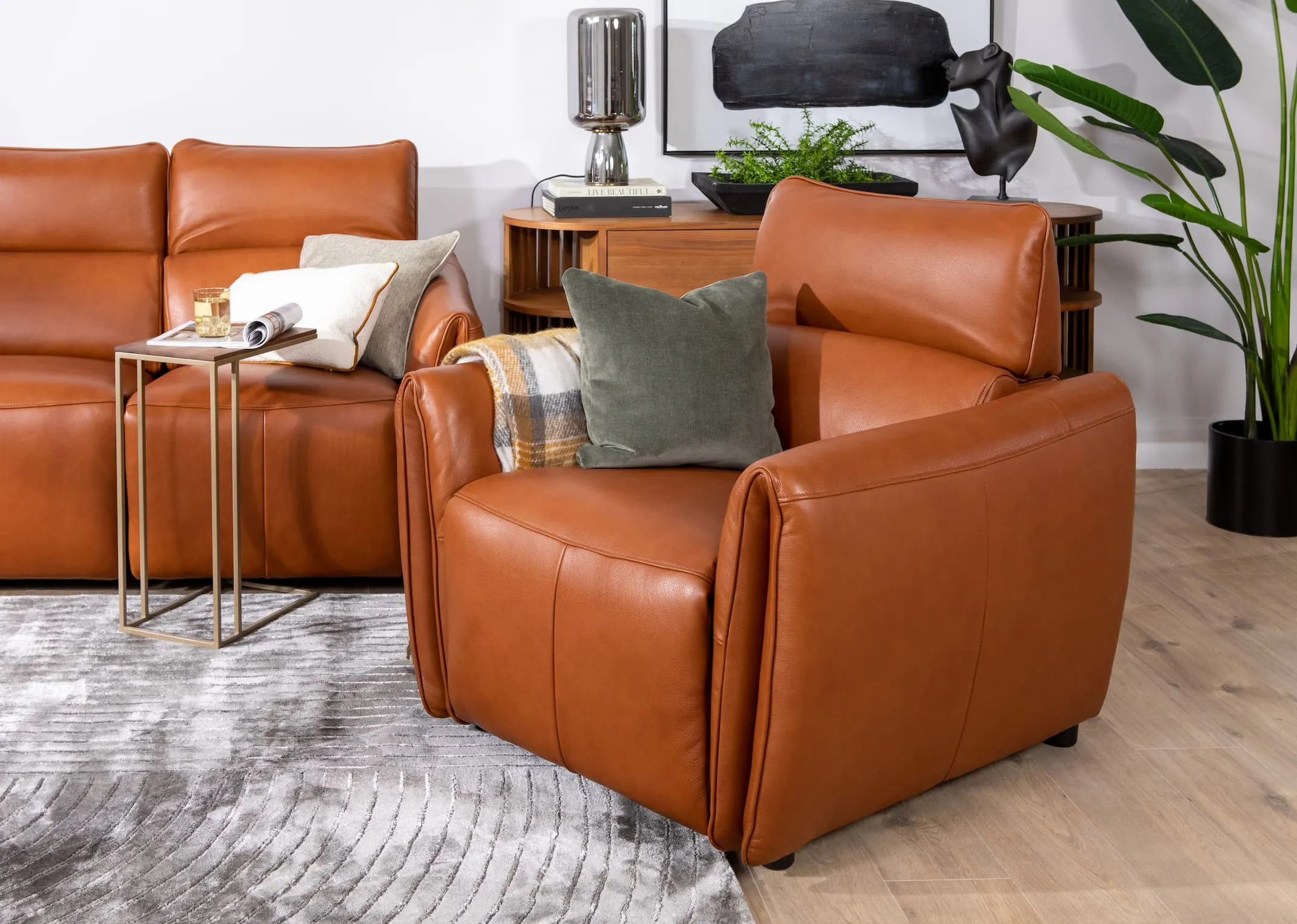 A tan leather power reclining sofa from EZ Livings Icon range. Angled view of tilted headrest and reclined seat