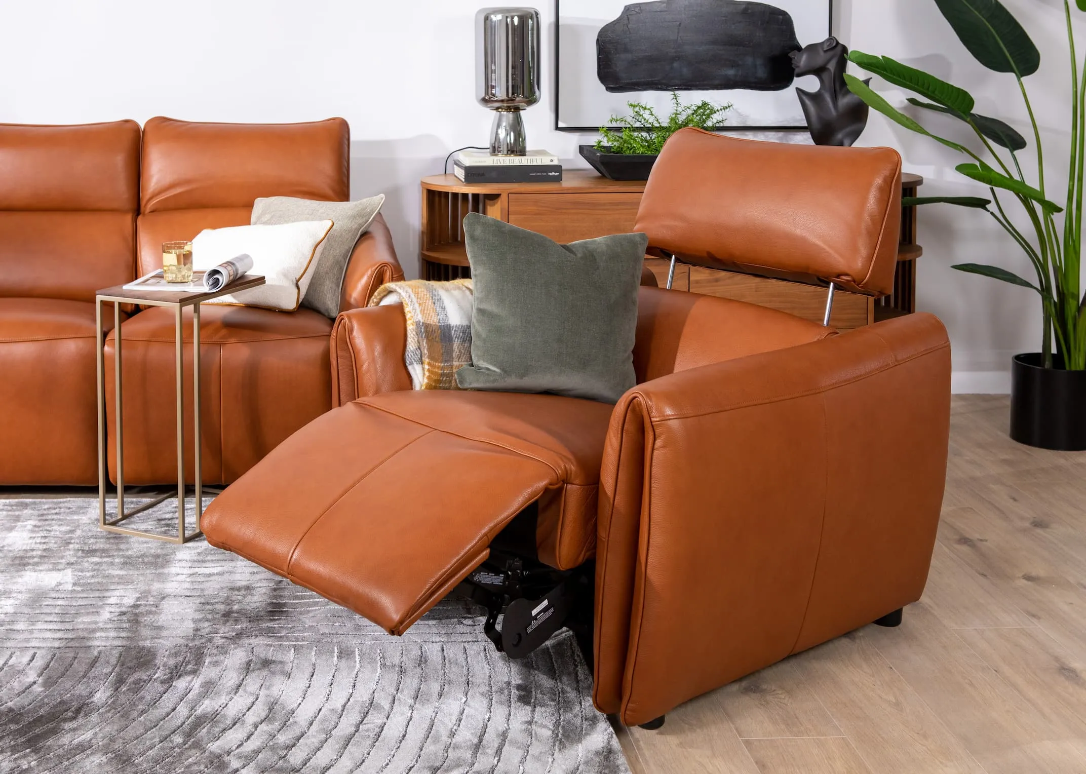 A lifestyle image of the Icon power recliner with green & cream cushions with Frida rug and Aston tables