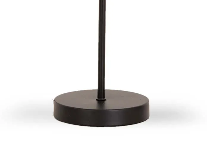 A black metal table lamp with round base and smoked glass shade from EZ Livings Karina range. Closeup of round metal base