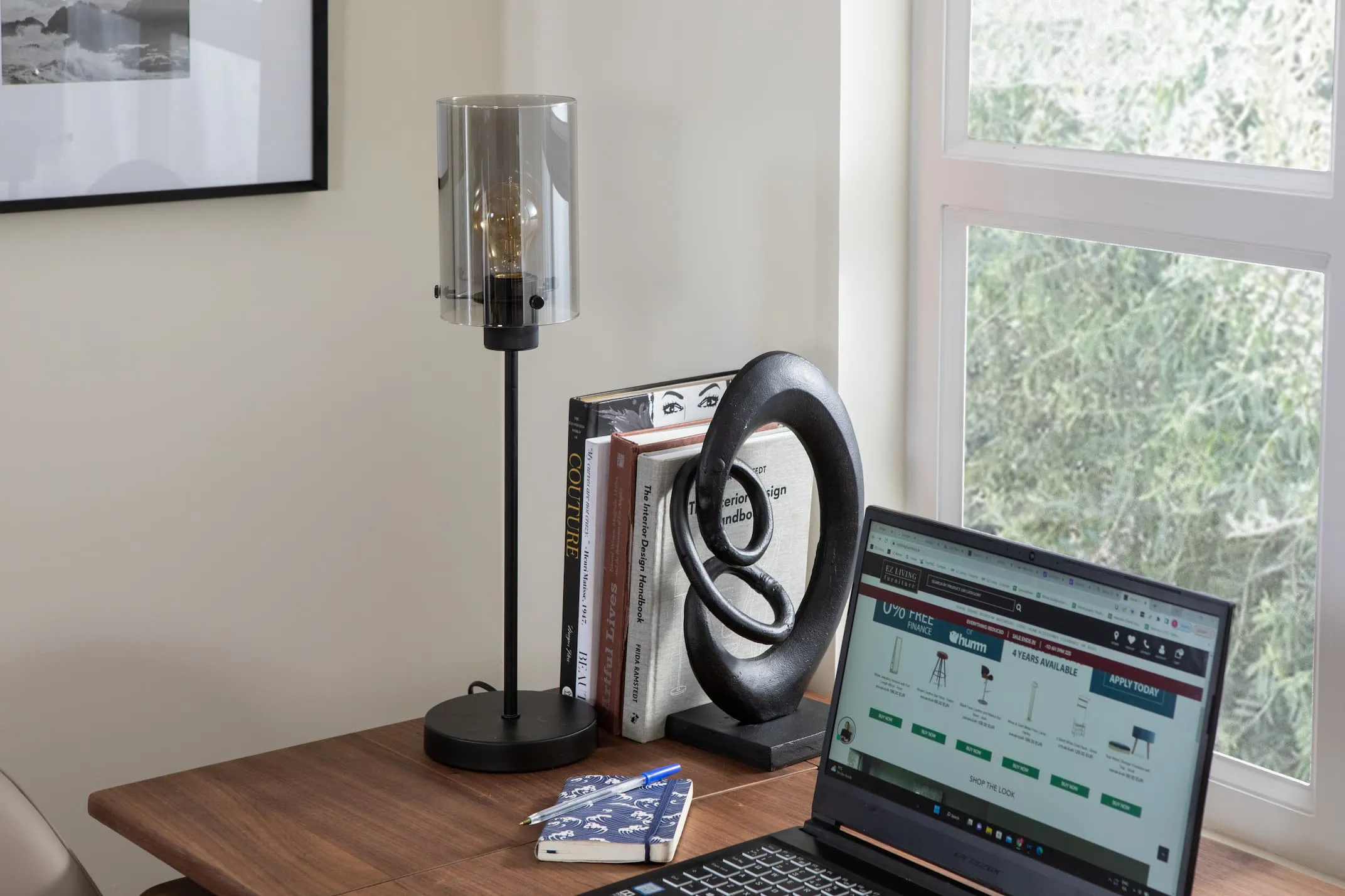 A lifestyle image of the Karina black lamp switched off with the Orbit desk with laptop