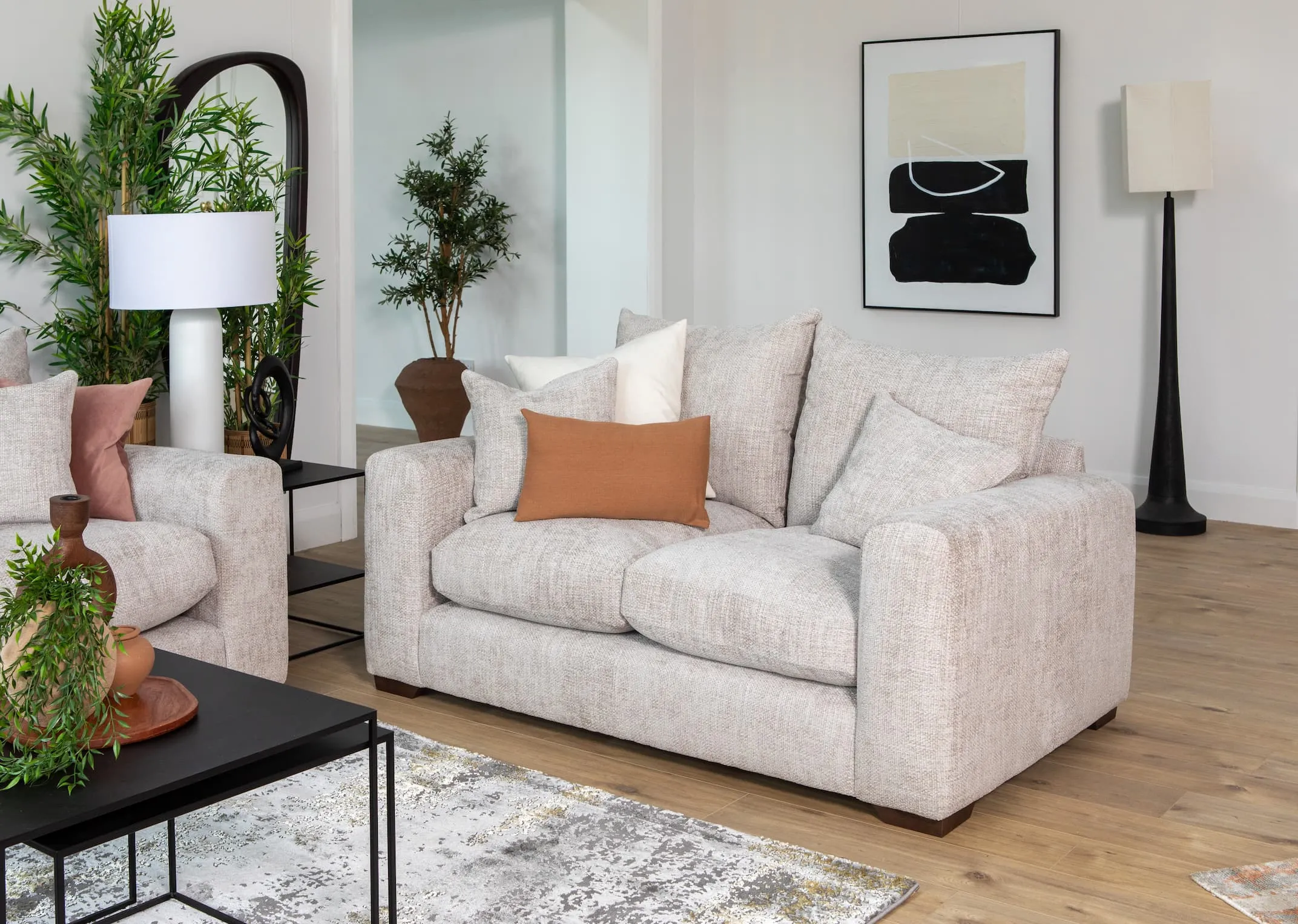 A lifestyle image of the Aurora 2 Seater sofa with pebble tables & Saturn table lamp with Inez mirror.