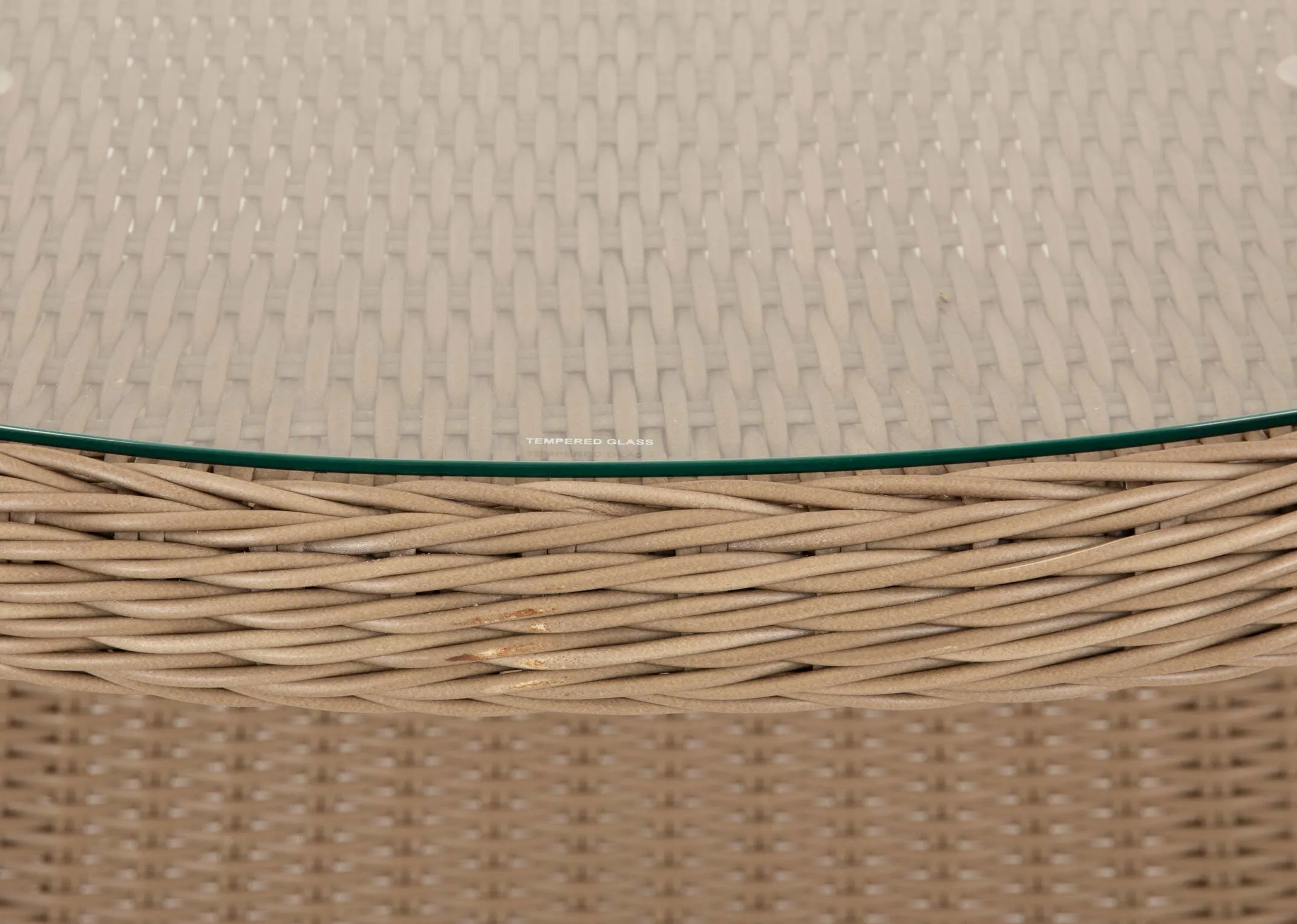 A glass top oval rattan garden dining table from EZ Livings Seville range. Closeup on hole in centre to accomodate parasol