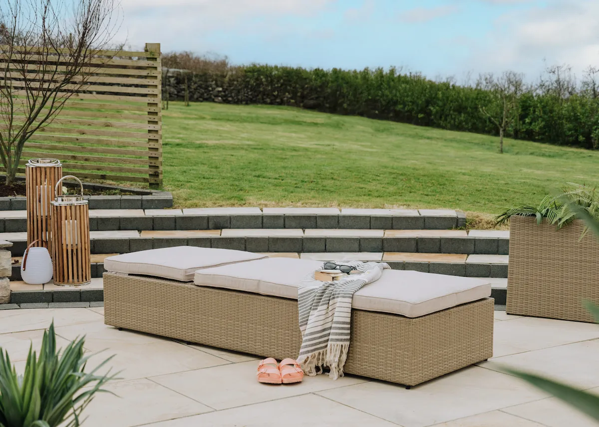 A light brown wicker sunlounger with a closeup shot on the light brown wicker and the adjustable headrest metal bar and settings under the lounger