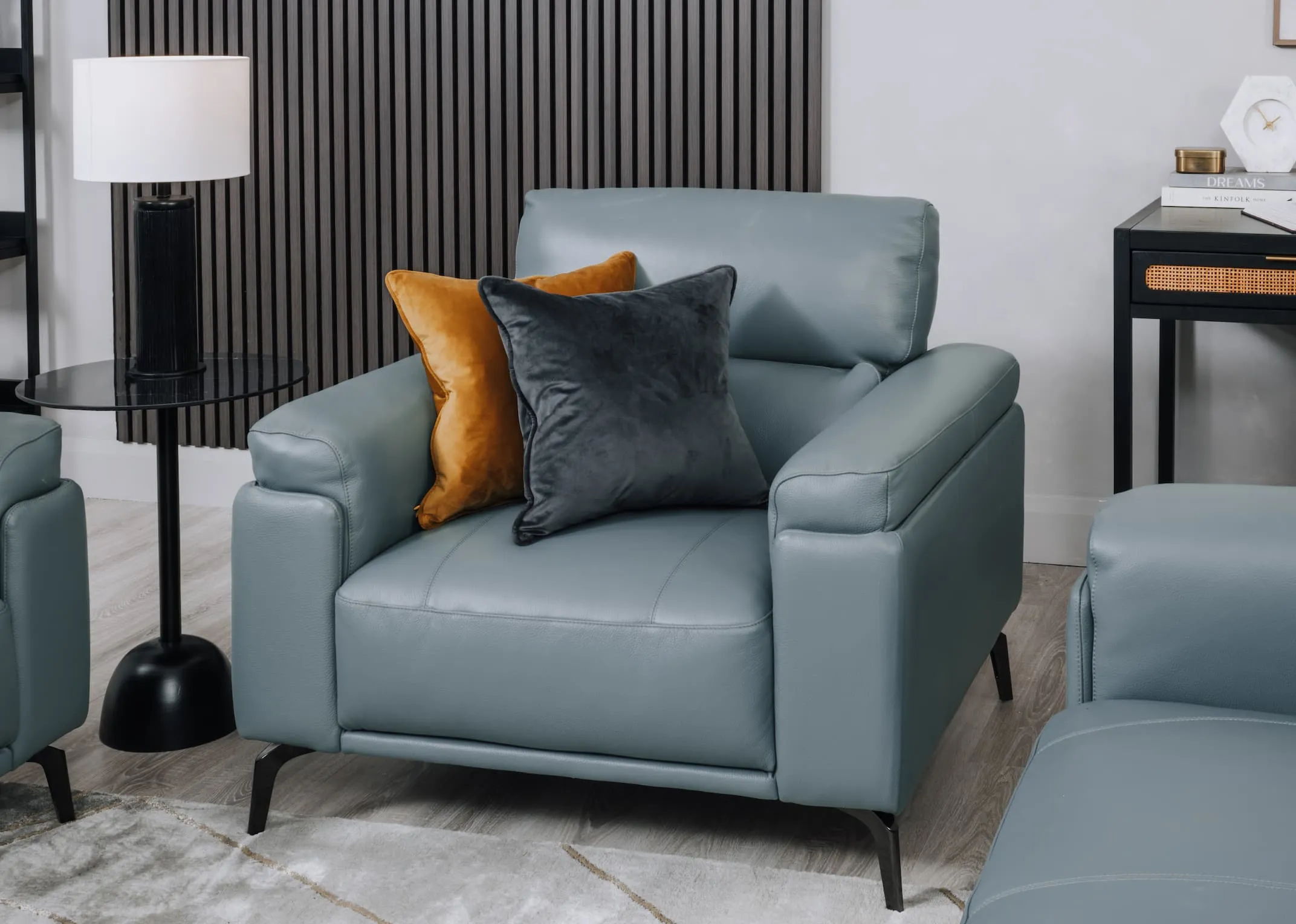 A lifestyle image of the Lagoon armchair with gold & black velevt cushions.