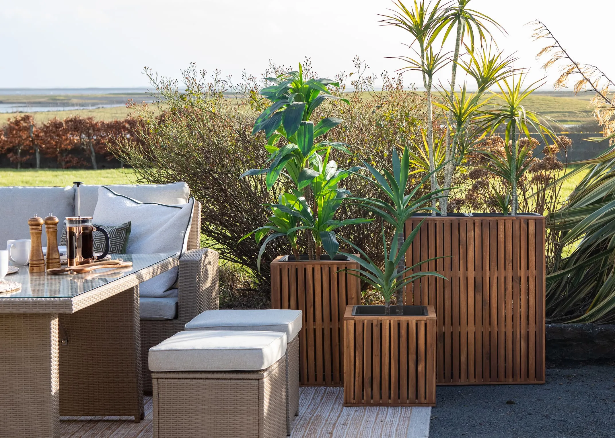 A lifestyle image of the Small Medium & Large Santa Cruz planters in an Outdoor setting with the Malaga Garden set