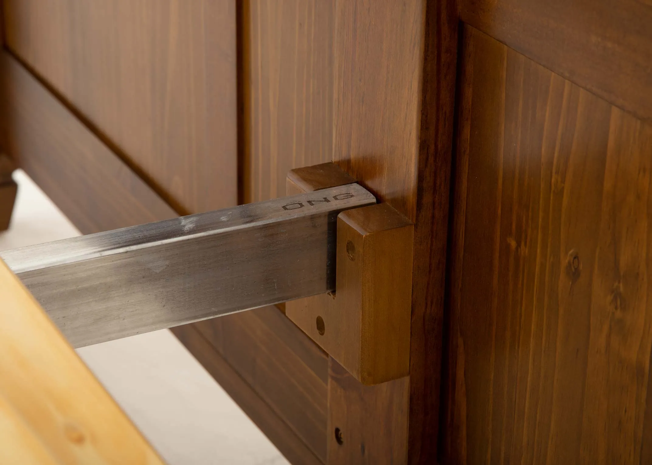 A brown pine bedframe from EZ Livings Allyson range. Closeup of metal bars attached bedframe to headboard