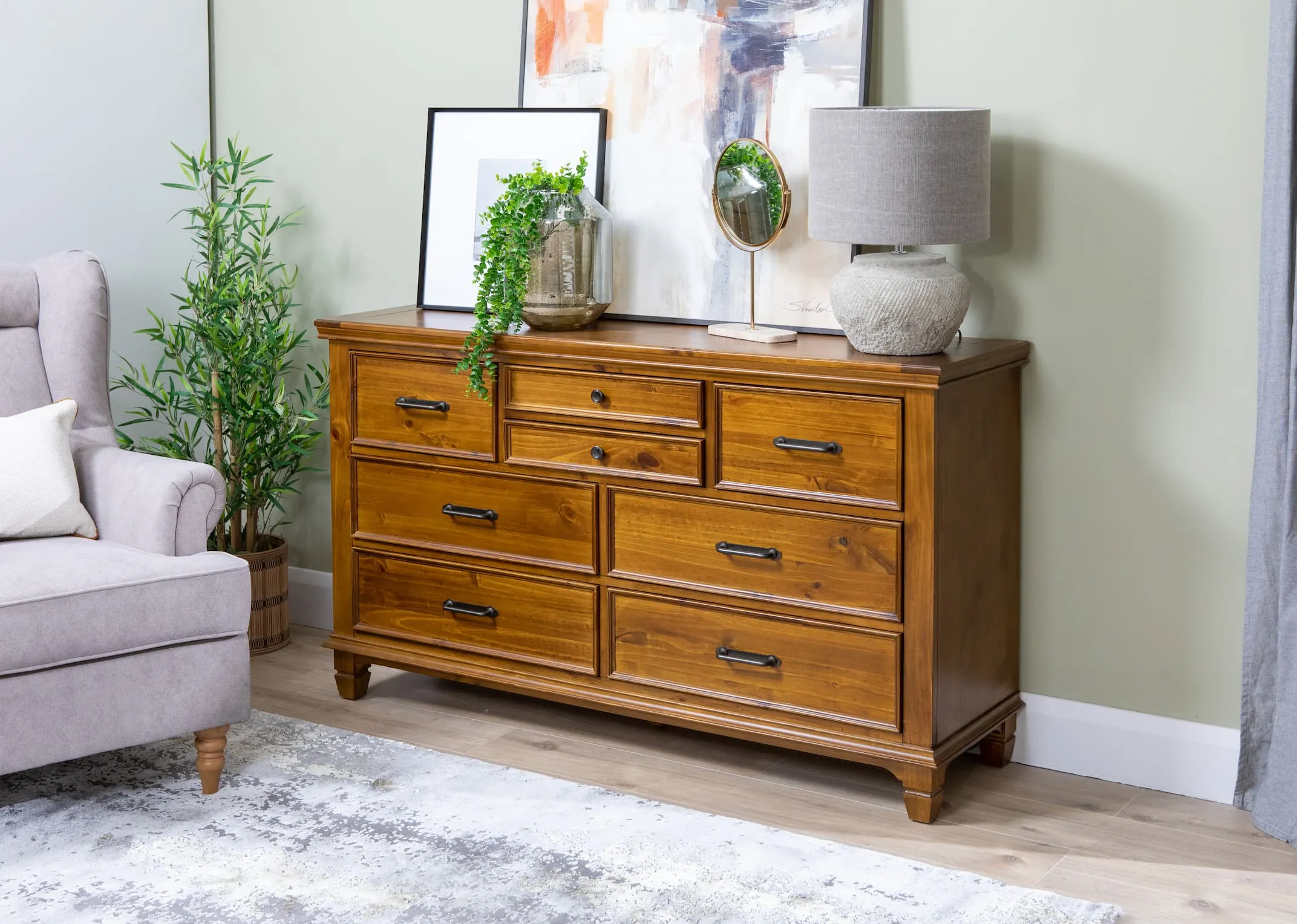 A lifestyle image of the Allyson Chest of 8 drawers with the astoria chair & Vertas lamp
