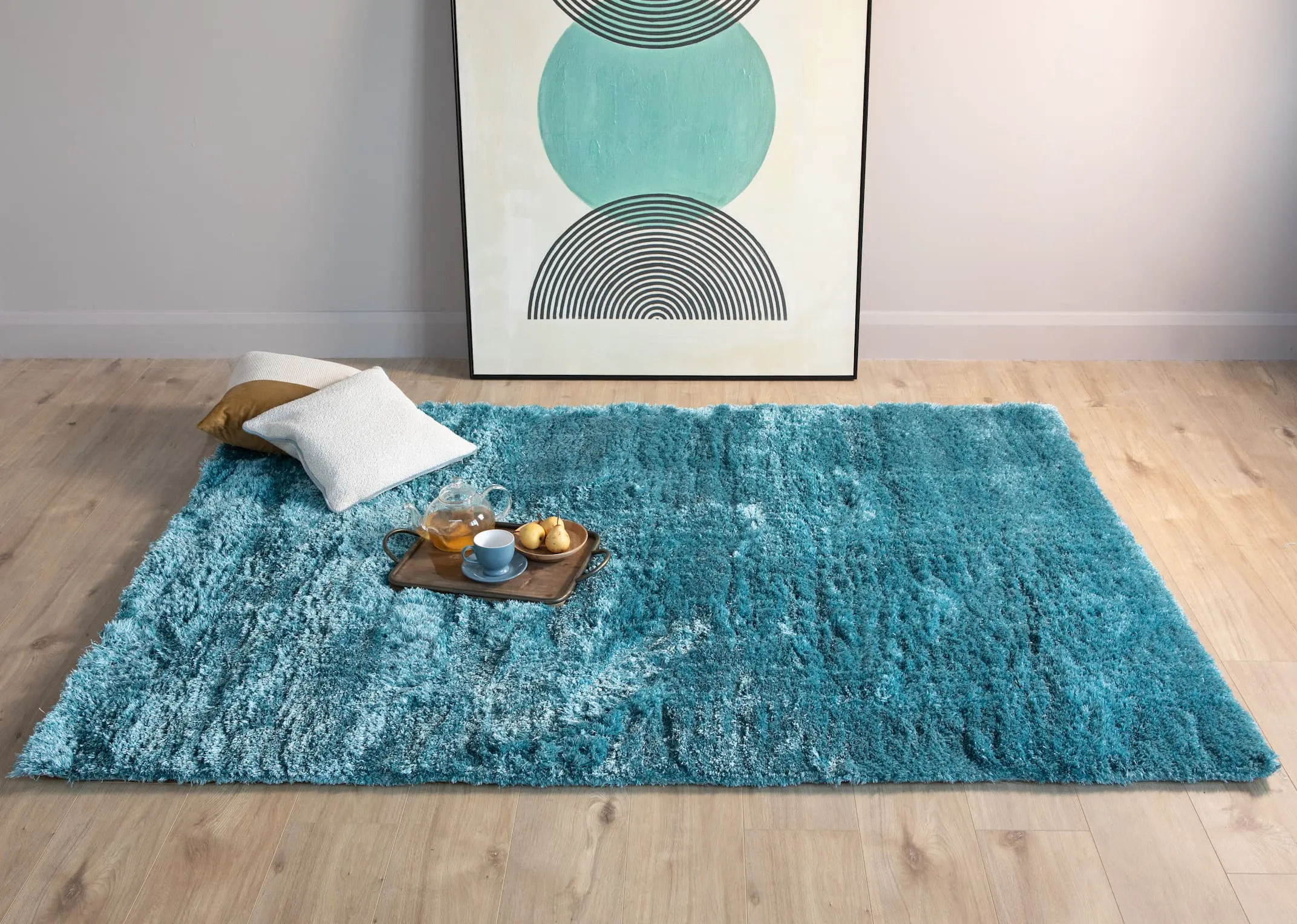 A lifestyle image of the Lux aqua rug with the Concept canvas with gold tray and cushions.