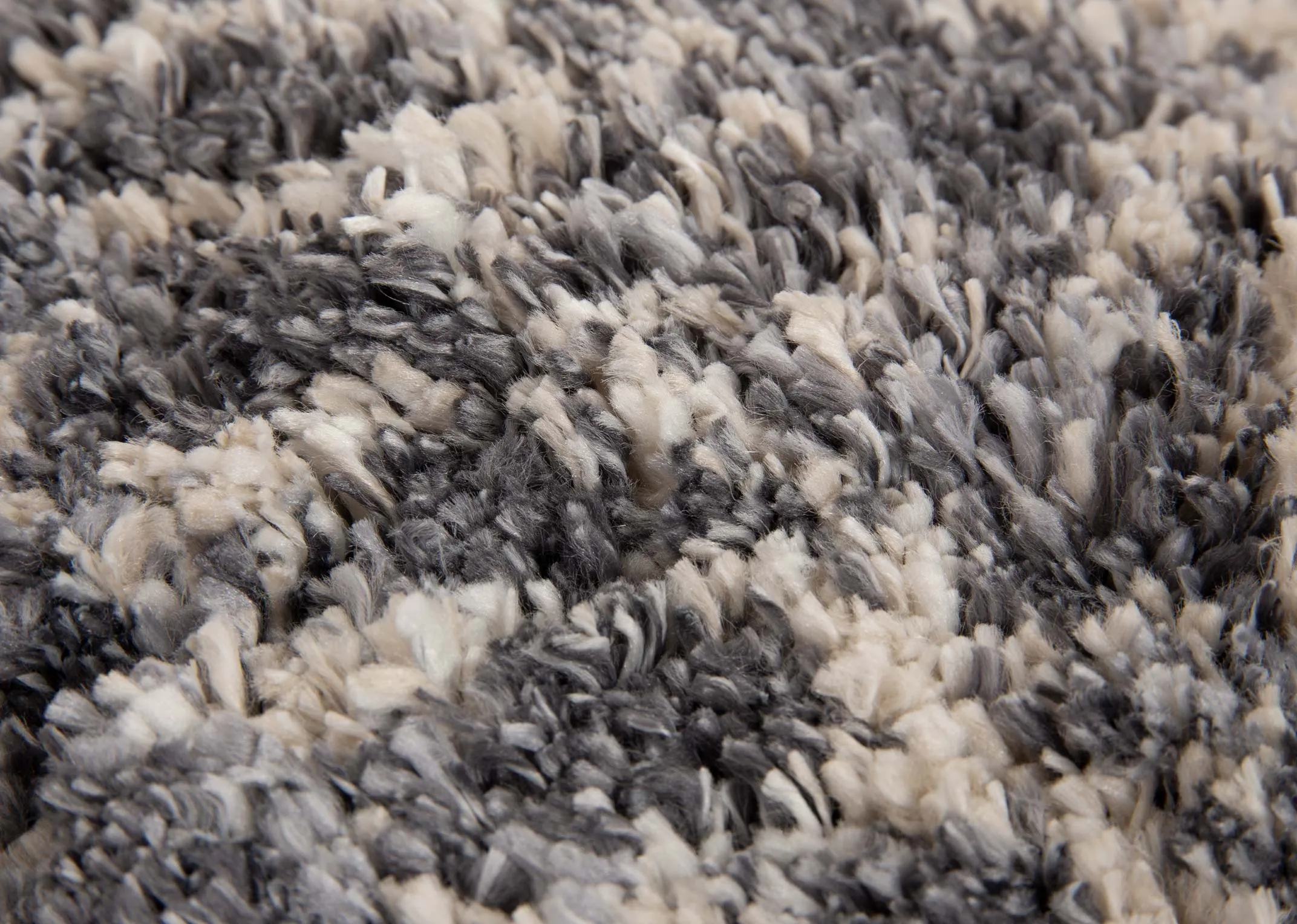 A dark grey deep pile rug with white Aztec print from EZ Livings Sula range. Closeup of soft texture