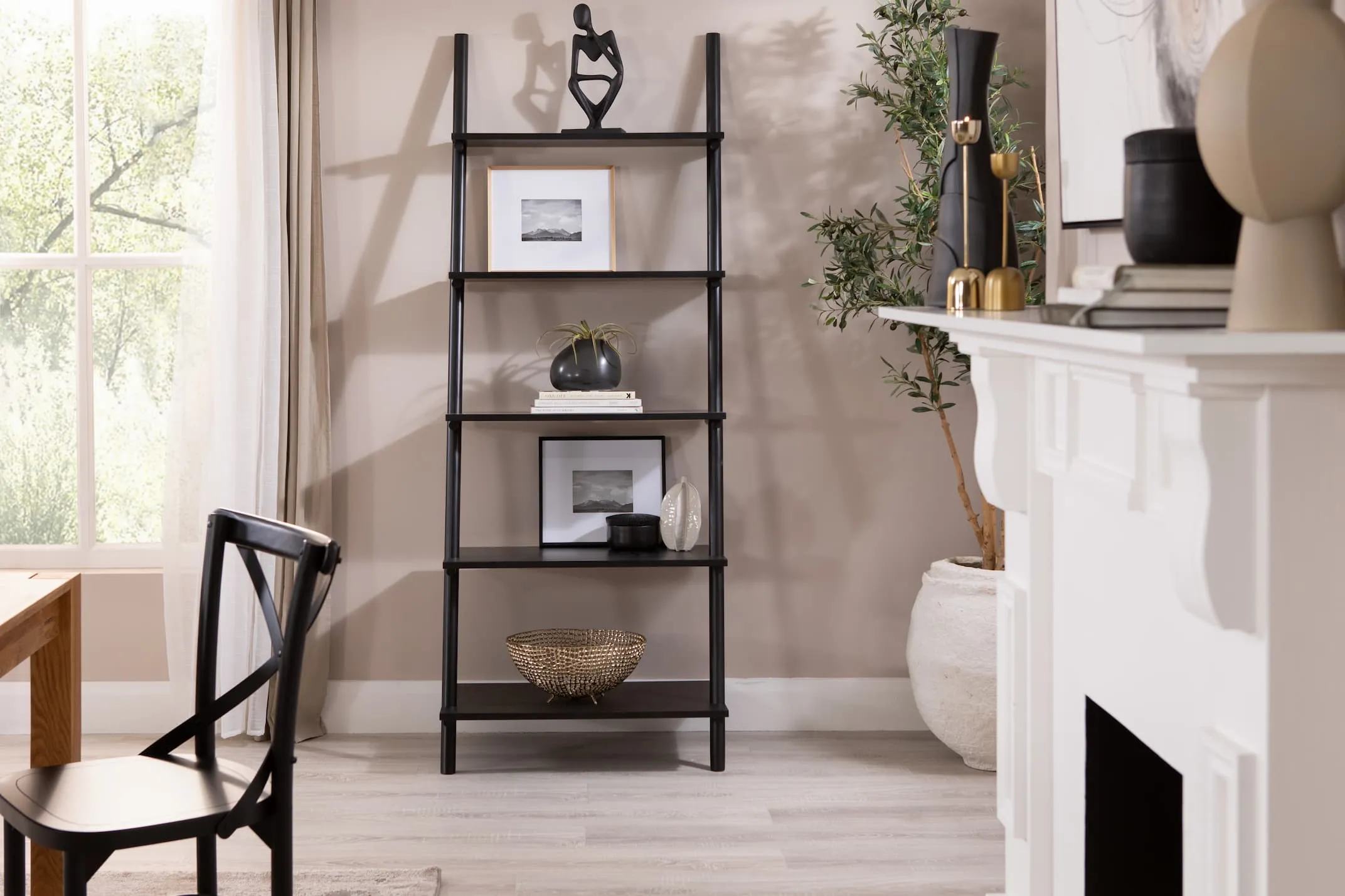 A lifestyle image of the Step small bookcase with a selection of EZ Livings photo frames ornaments & home decor with Olive plant.