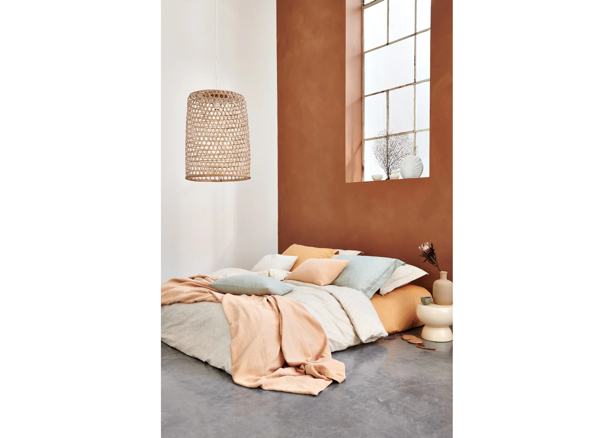A lifestyle image of a loft style bed on cement floor with Geometrical duvet cover paired with smoke green and blush pillows and linen from Van Dyck.
