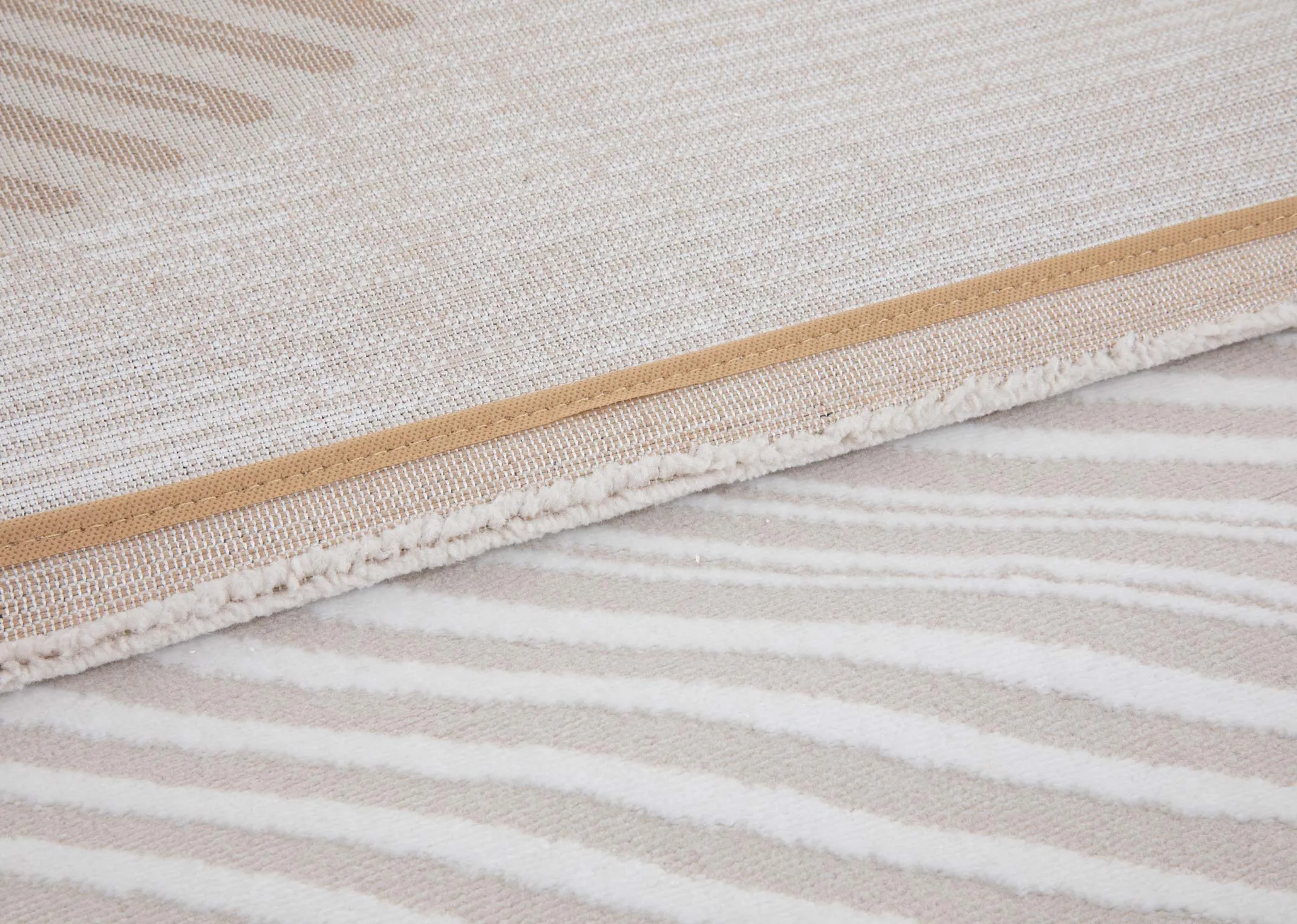 A beige rug with brown cream gold and orange metallic design from EZ Livings Creation range. Closeup of underlya