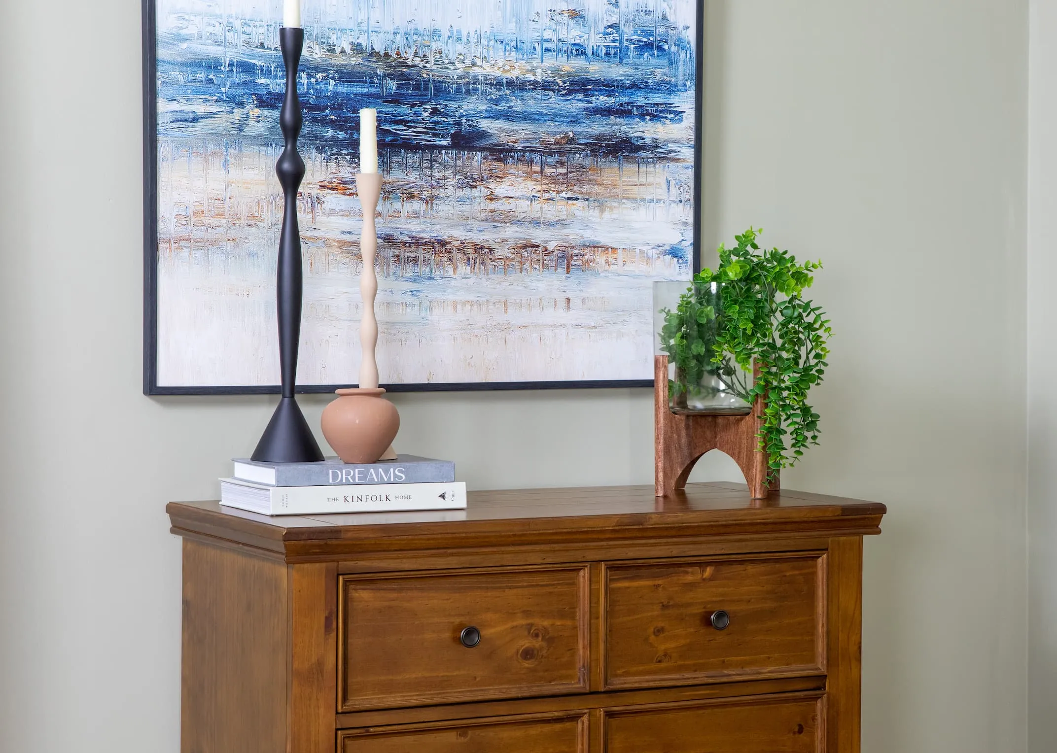 A lifetsyle image of the Jace vase with foliage on the Allyson Dresser and a selction of candle holders.