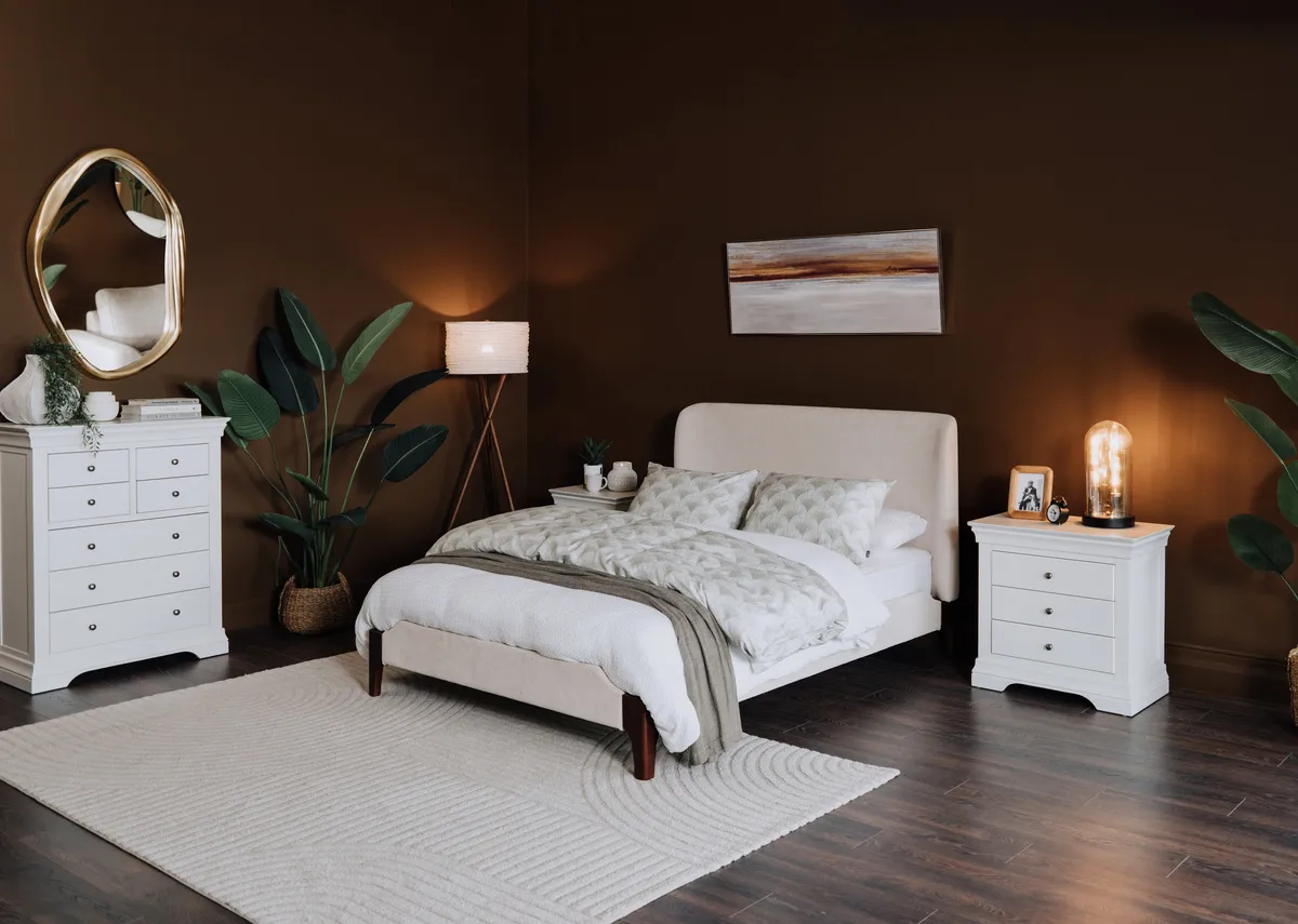 A lifestyle image of the Calm beige bedframe with Delfina mirror and Amelie chest and locker.
