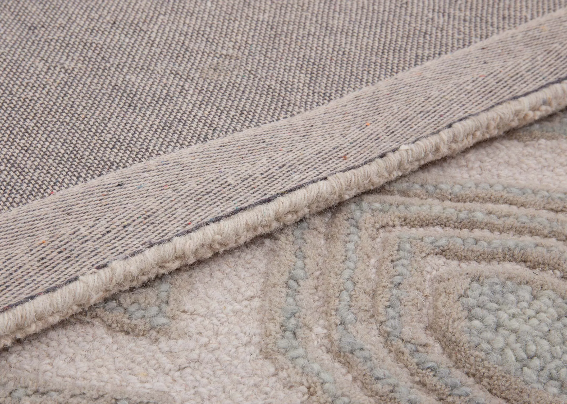 A beige honeycomb print rug from EZ Livings Elio range. Closeup of underlay.
