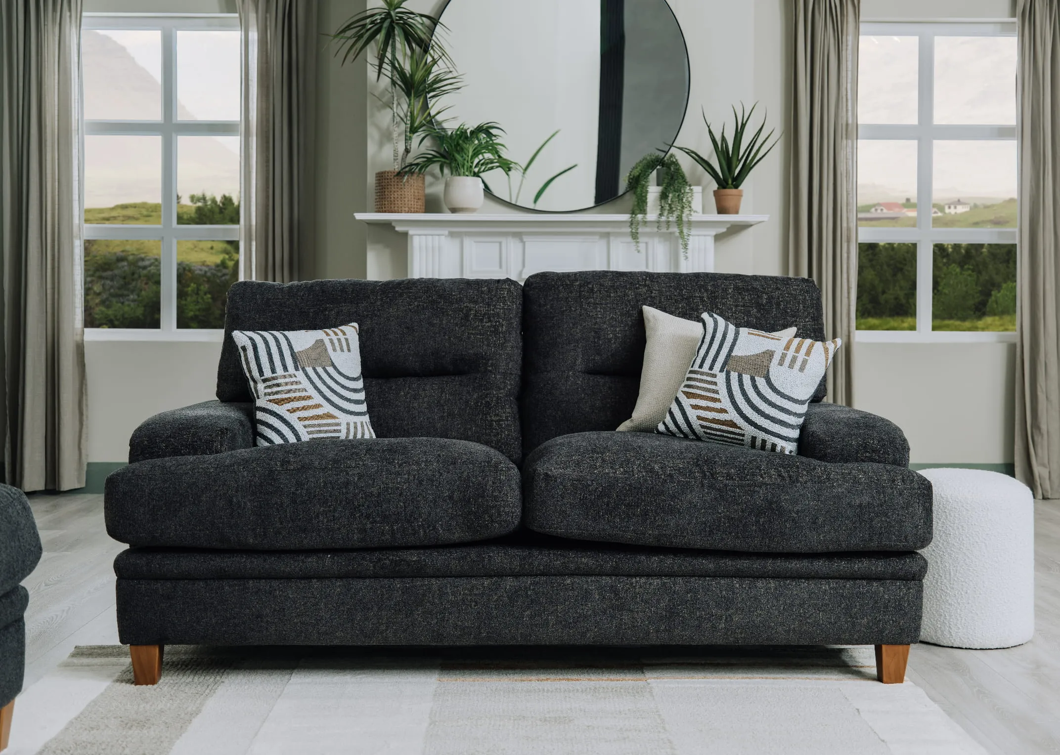A lifestyle image of the Trieste 2 Seater sofa with geo cushions with elling mirror and parker footstool.