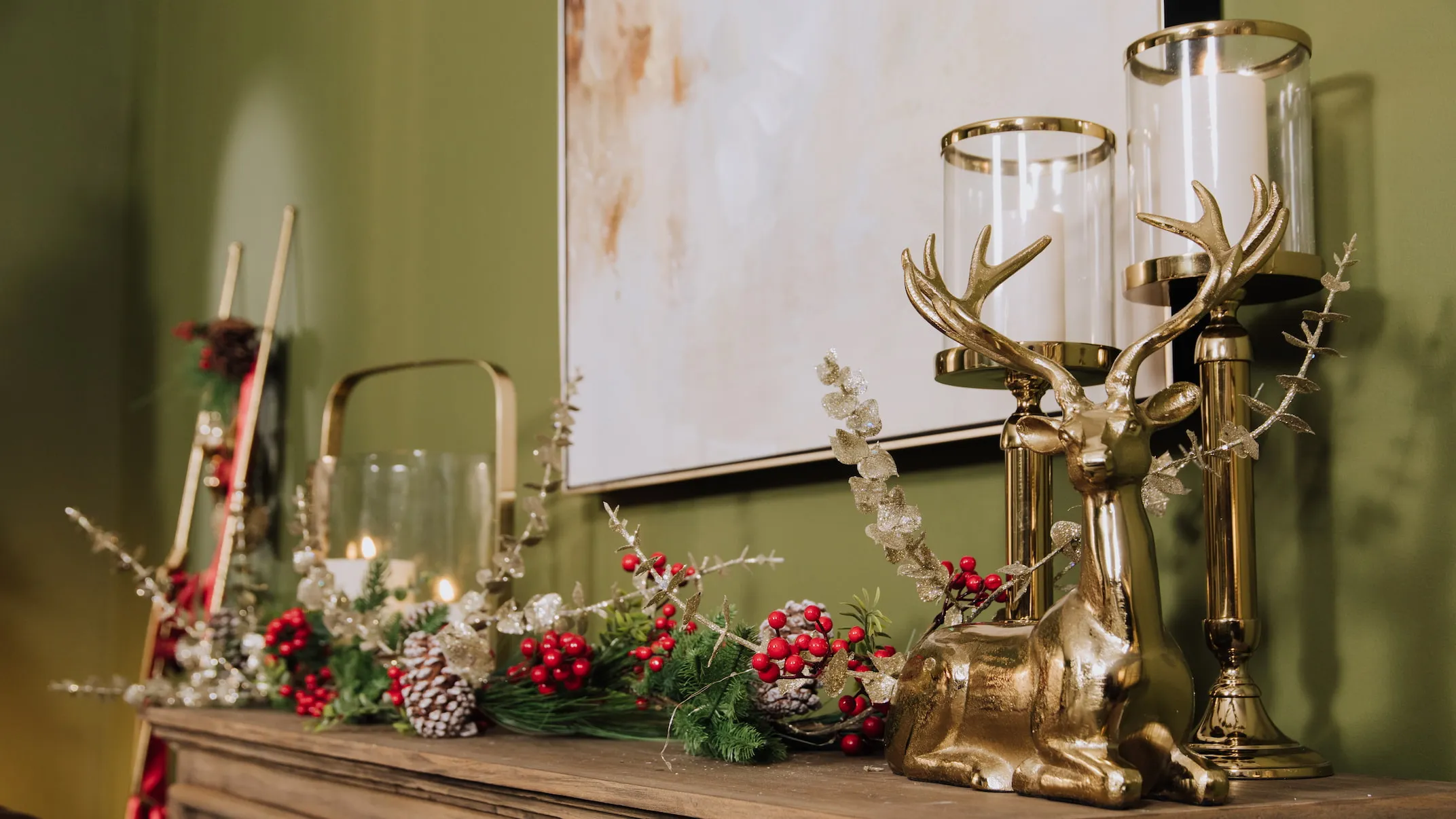 A lifestyle image of a Sideboard with sitting reindeer ornament & Medium & Small Pillar Candle Holders.