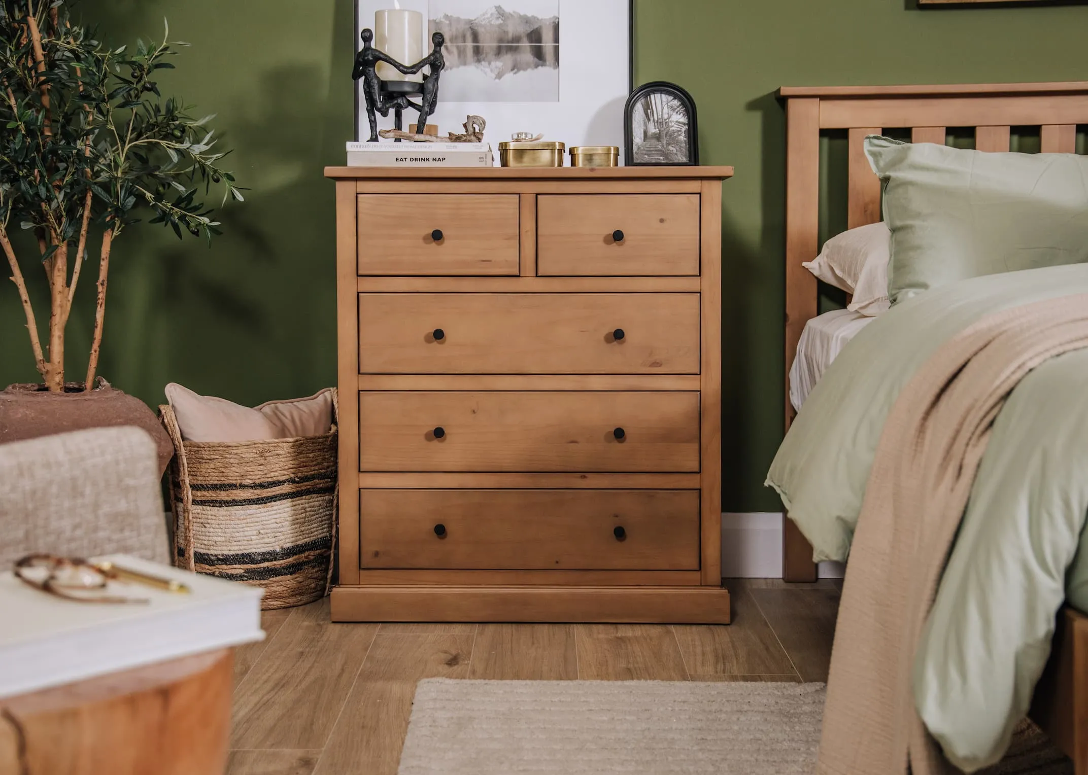 A lifestyle image of the Atlas rustic chest beside the bedframe dressed with photo frames and onraments all from EZ Living Furniture!