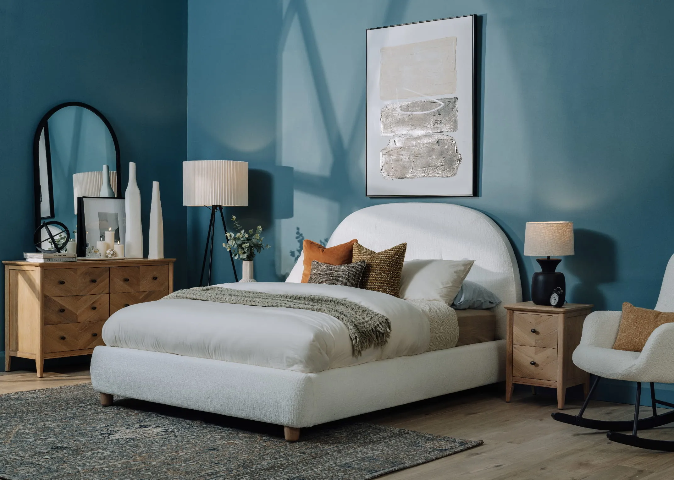 A lifestyle image of the Joelle bedframe with brown knitted cushion the chevron oak locker and chest and maxima rug.