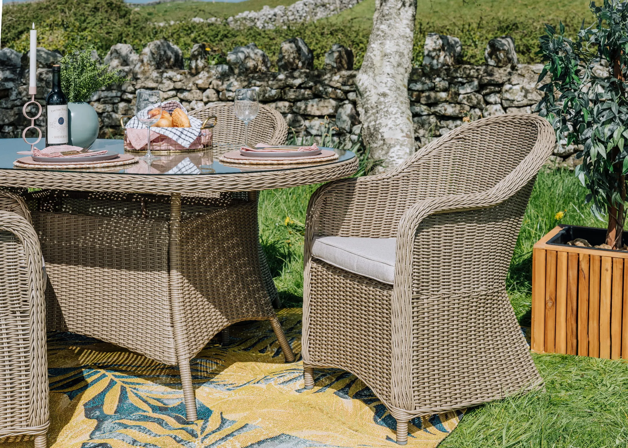 A lifestyle image of the Seville round back chair with round table in a garden setting.