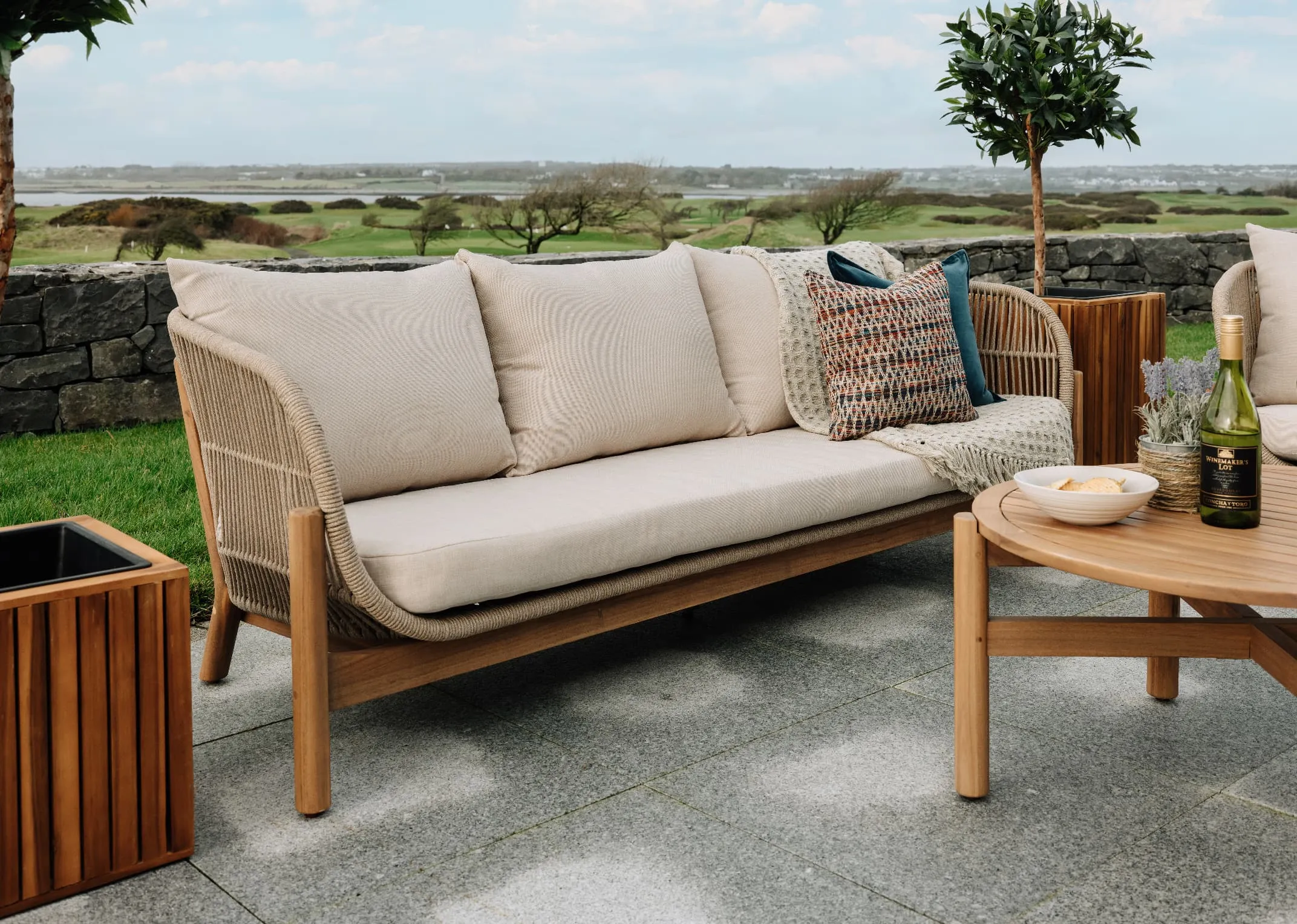 A lifestyle image of the La Palma Garden set with 3 seater closeup dressed with cushions and Santa cruz planter.