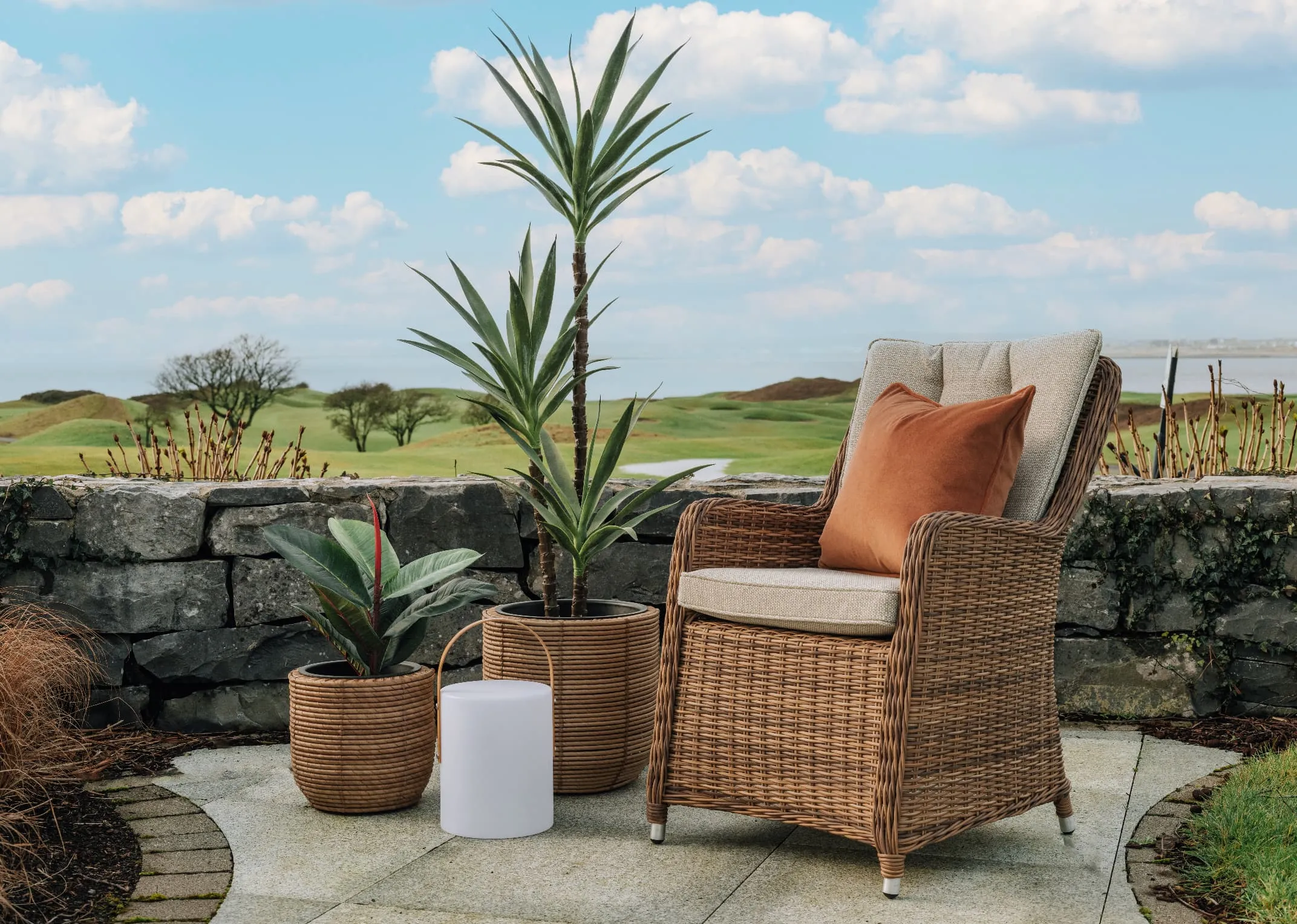 A lifestyle image of the Spica Outdoor LED Table Lamp with Brisbane Armchair with planters